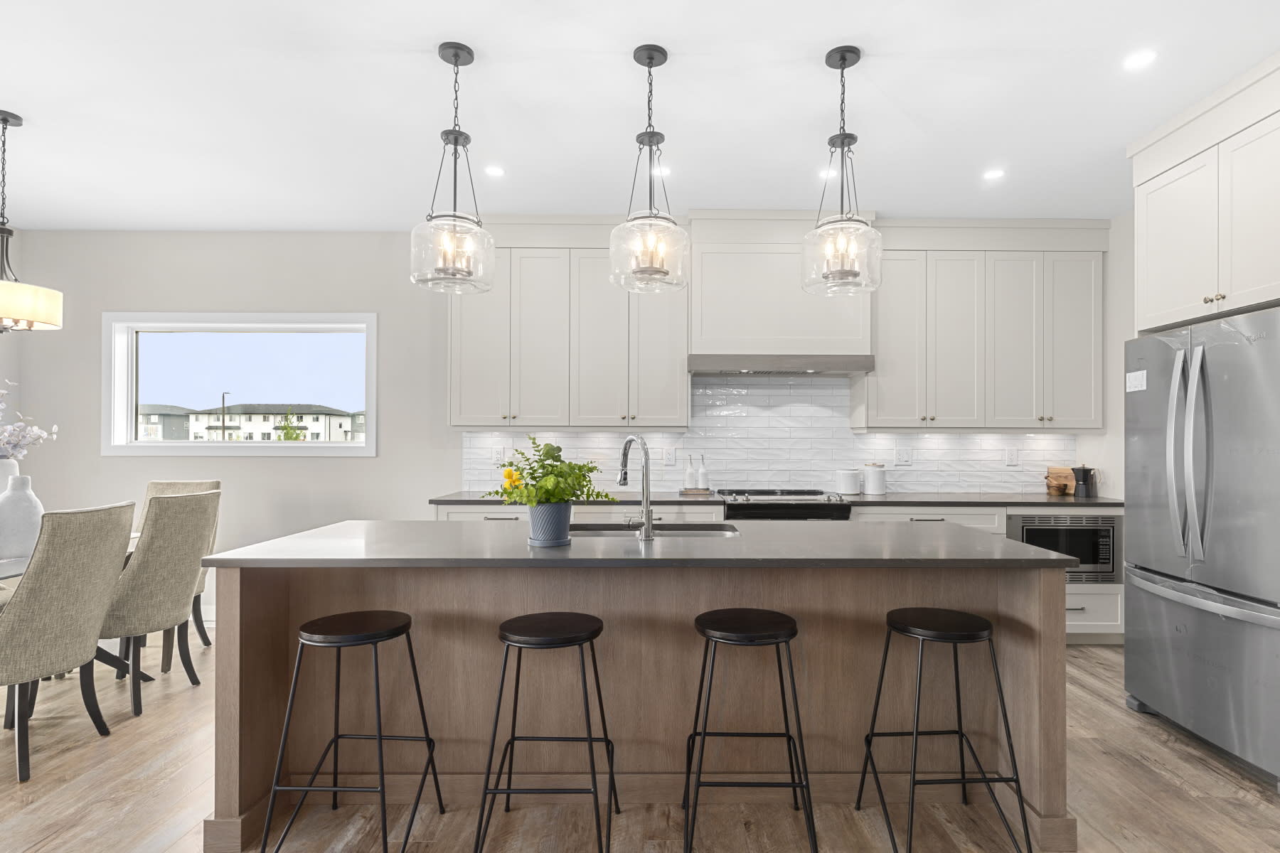 Designer kitchen with painted cabinets to ceiling with wood accents and island. Large island with designer light fixtures and