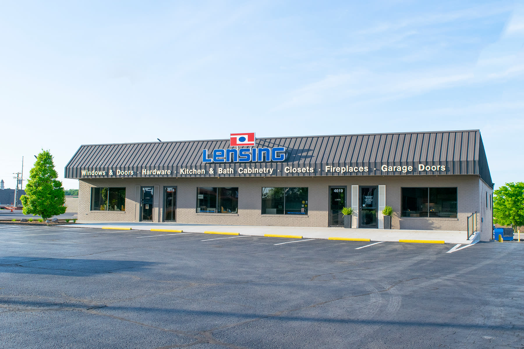 retail storefront with light brick and dark aluminum roof and Lensing logo in the middle of roof