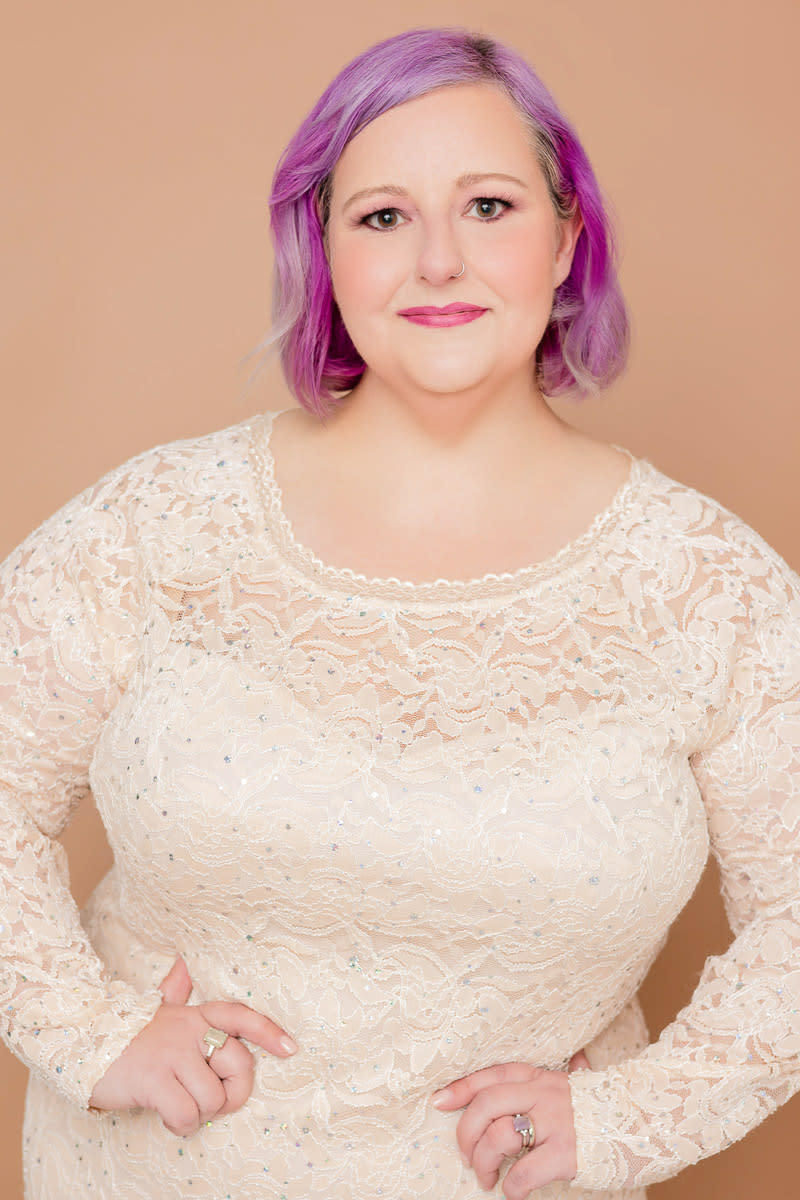 Headshot of woman with purple hair in white lace dress