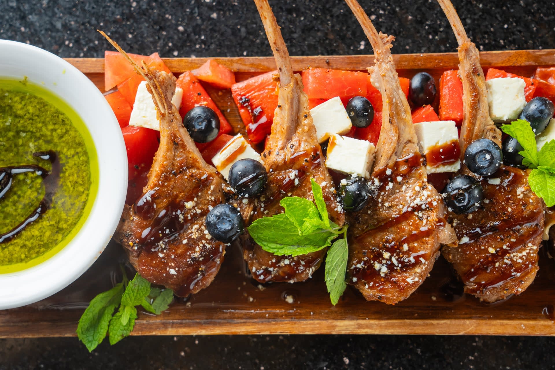 Grilled lamb lollipops served over watermelon, feta, and blueberries with fresh mint and chimichurri at Creekside