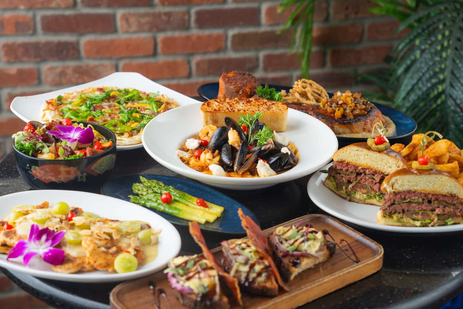 Assorted Creekside American Bistro entrées including seafood stew, gourmet burgers, salads, flatbread, and appetizers