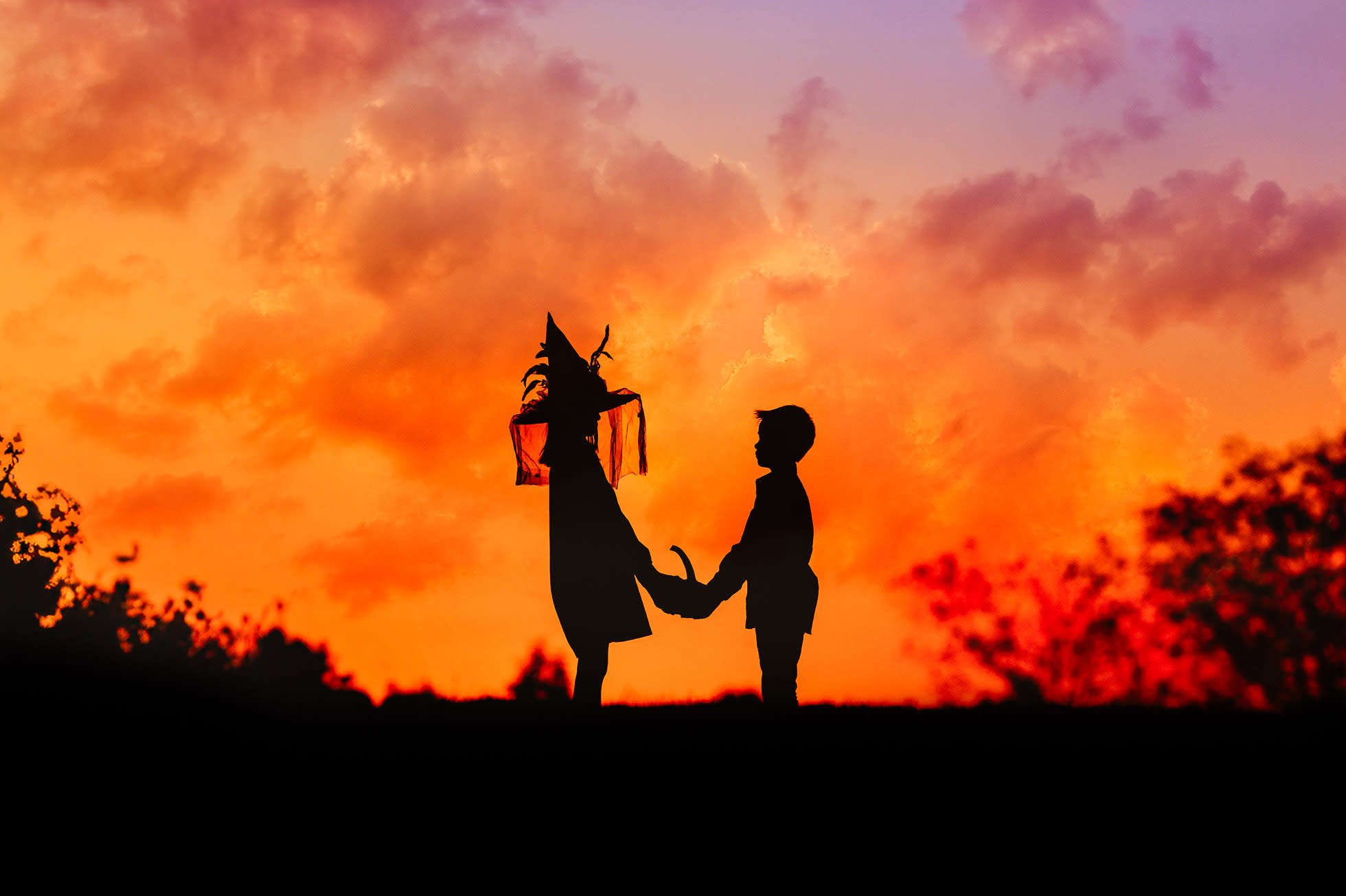 Halloween. Two children silhouette holding a pumpkin. Red sky in the background. Image taken ny helena Goessens Photography