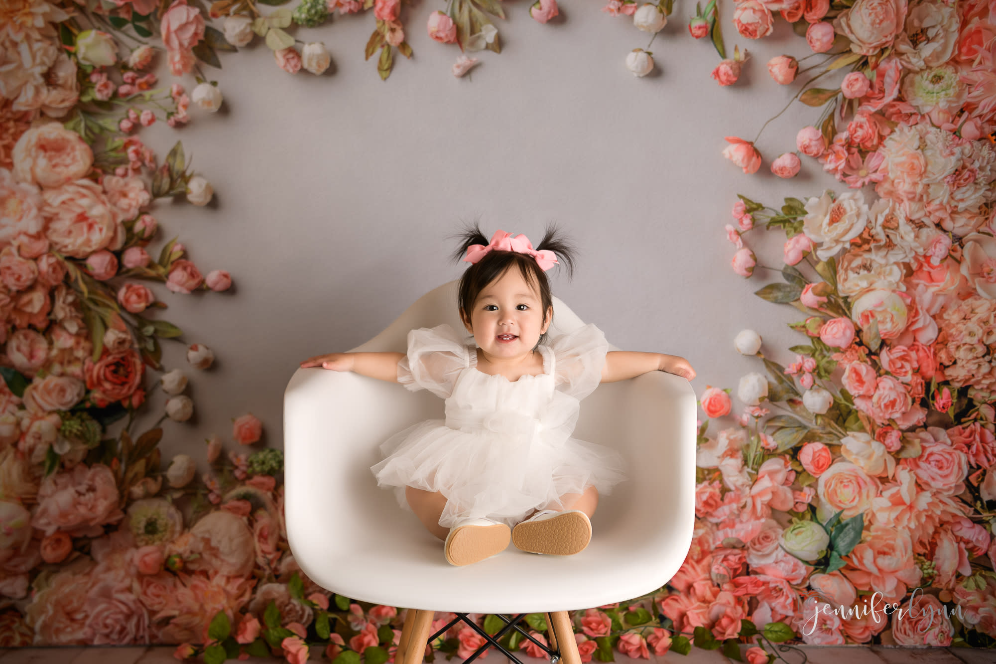 Peach and pink flower wall with one year old baby girl