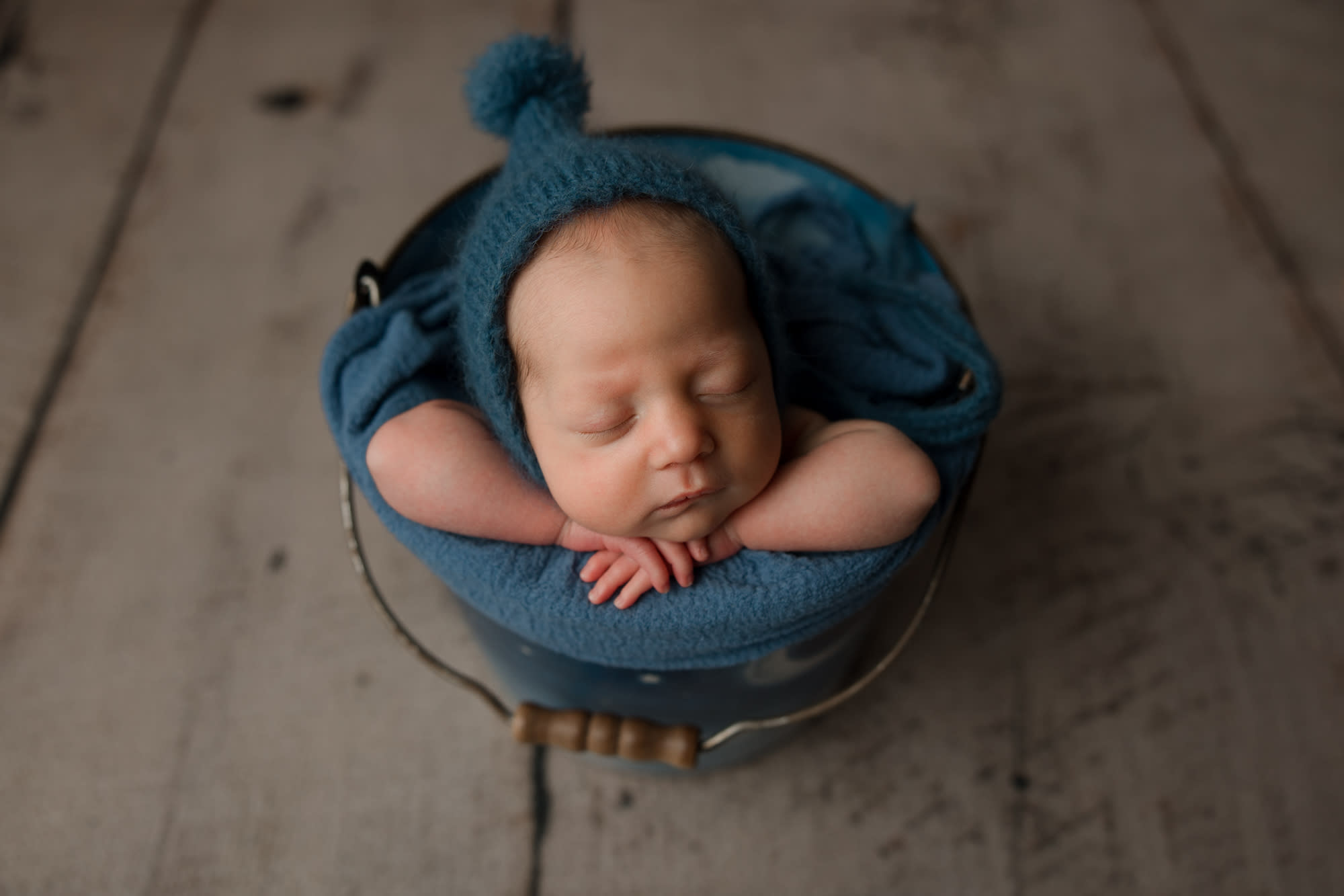 Sleeping baby in a bucket with blue hat