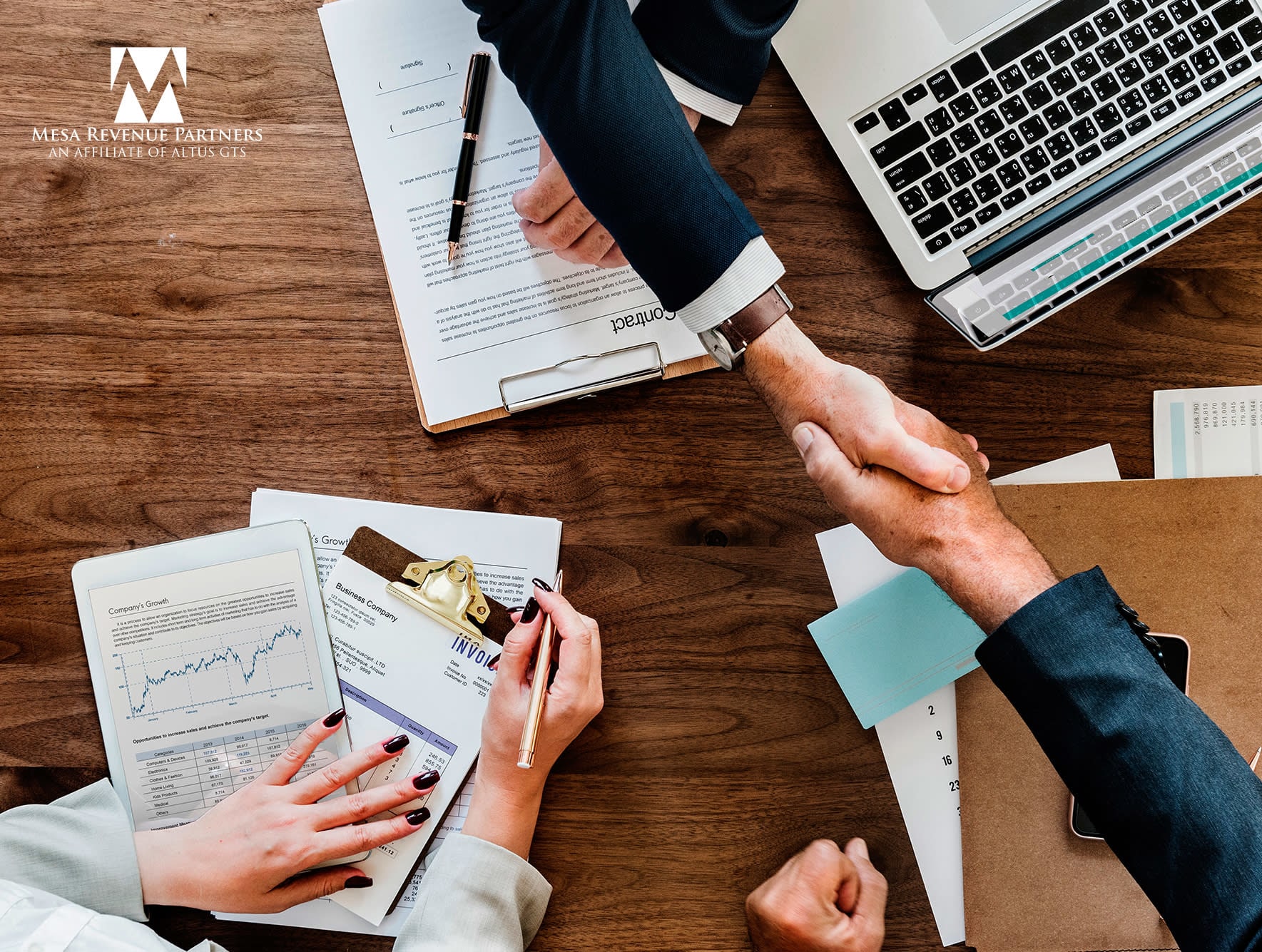 Business professionals shaking hands over laptops and papers, symbolizing collaboration in debt collection across Arizona and