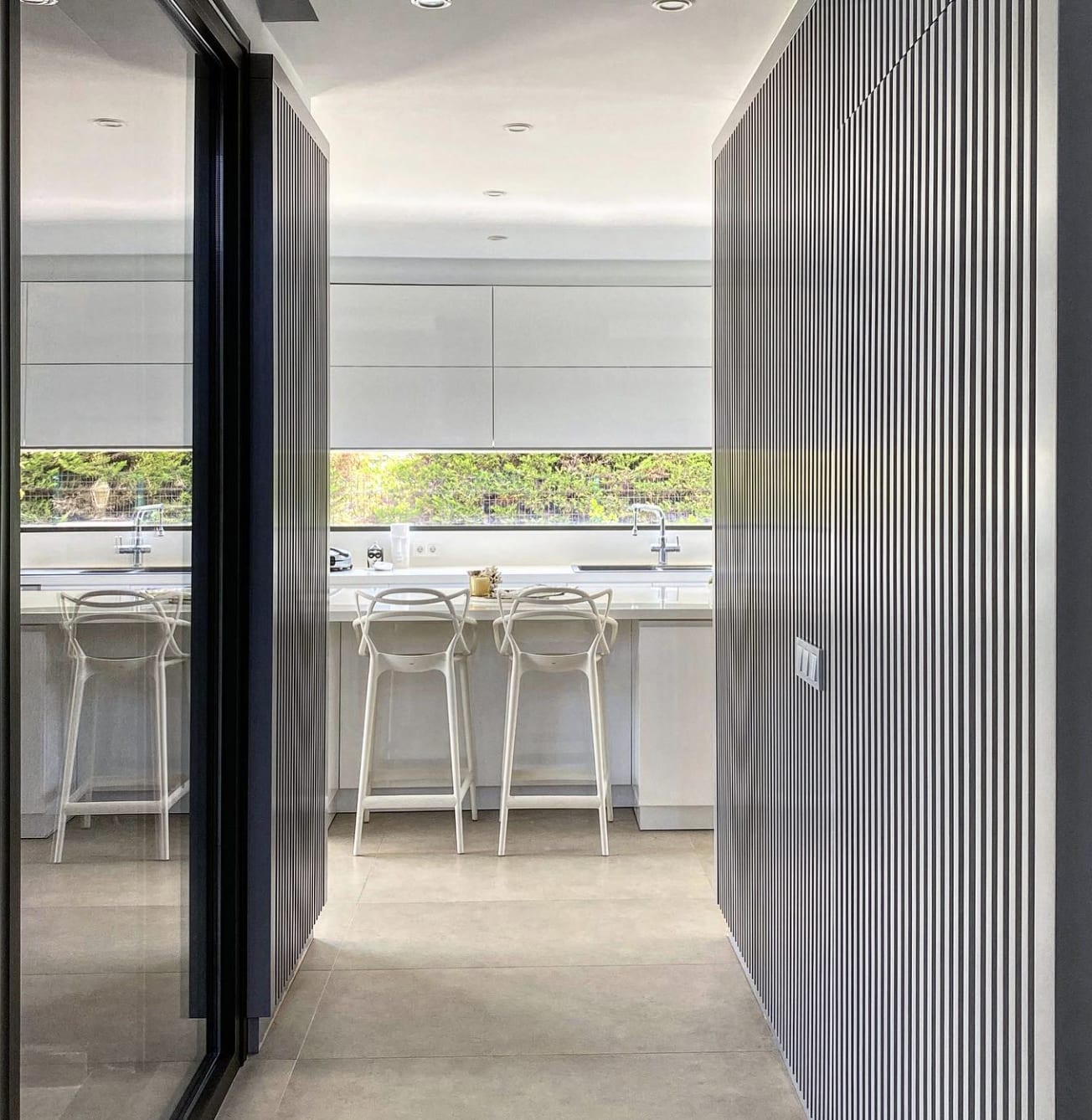 Ultra-modern fluted kitchen with custom vertical slatted cabinet doors, integrated appliances and a bright white island, craf