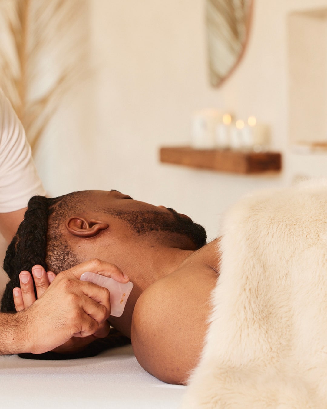 Massage therapist using Gua Sha stone enhancement on male client at The NOW Oak Lawn