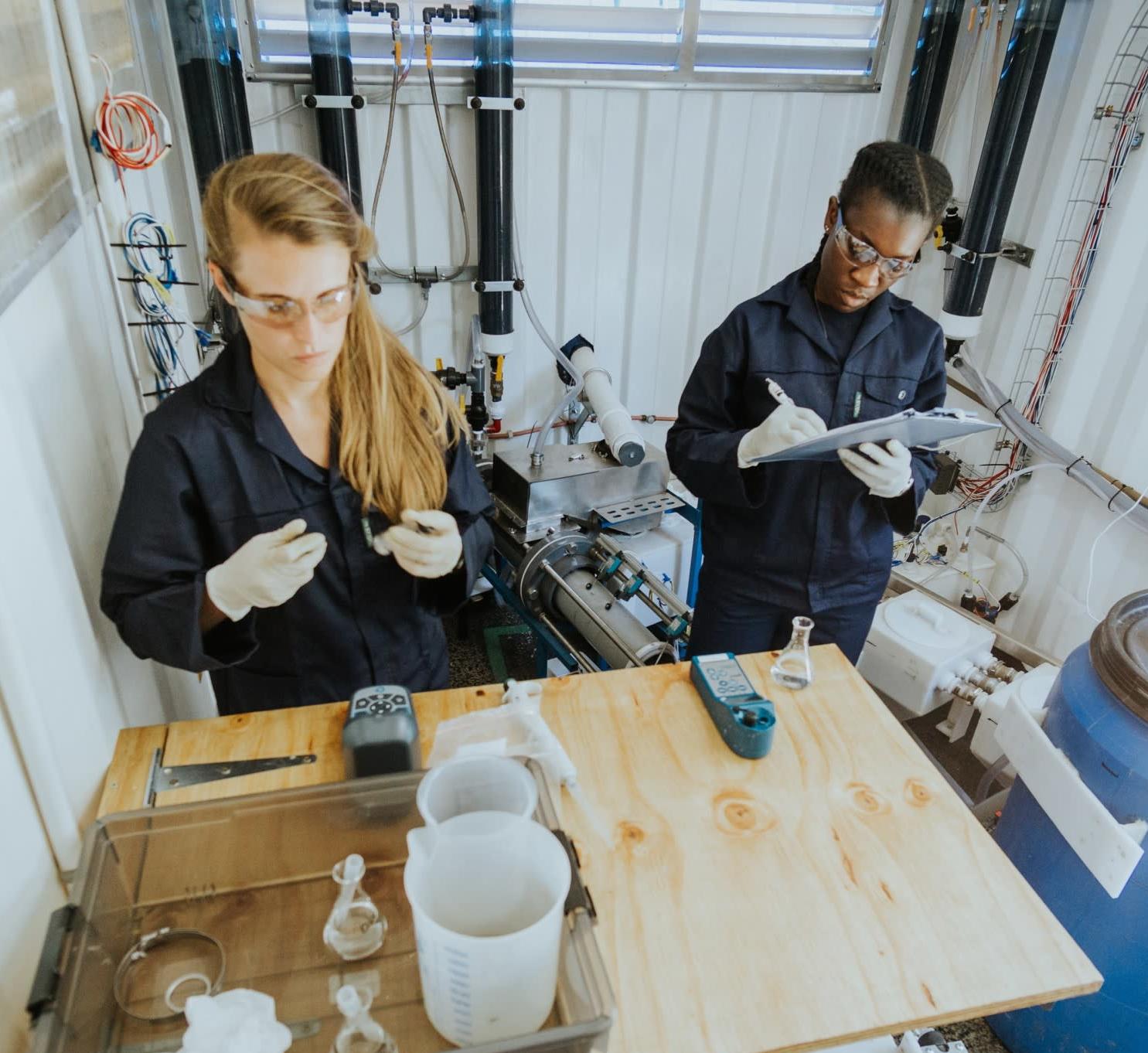 Two women collecting data from water samples from a non-sewered sanitation technology.