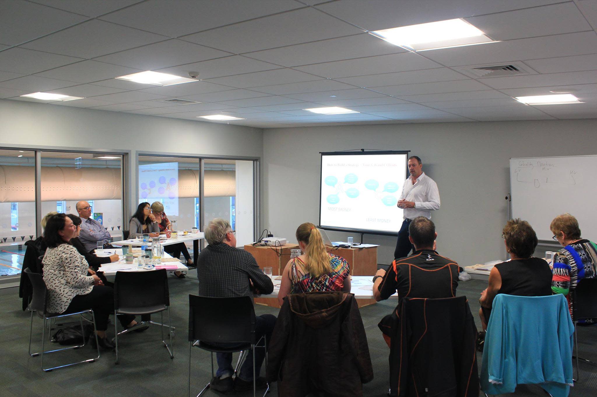 SBNZ event hosted in Hamilton, taken inside a conference centre. Man standing at front, presenting to NZ business owners