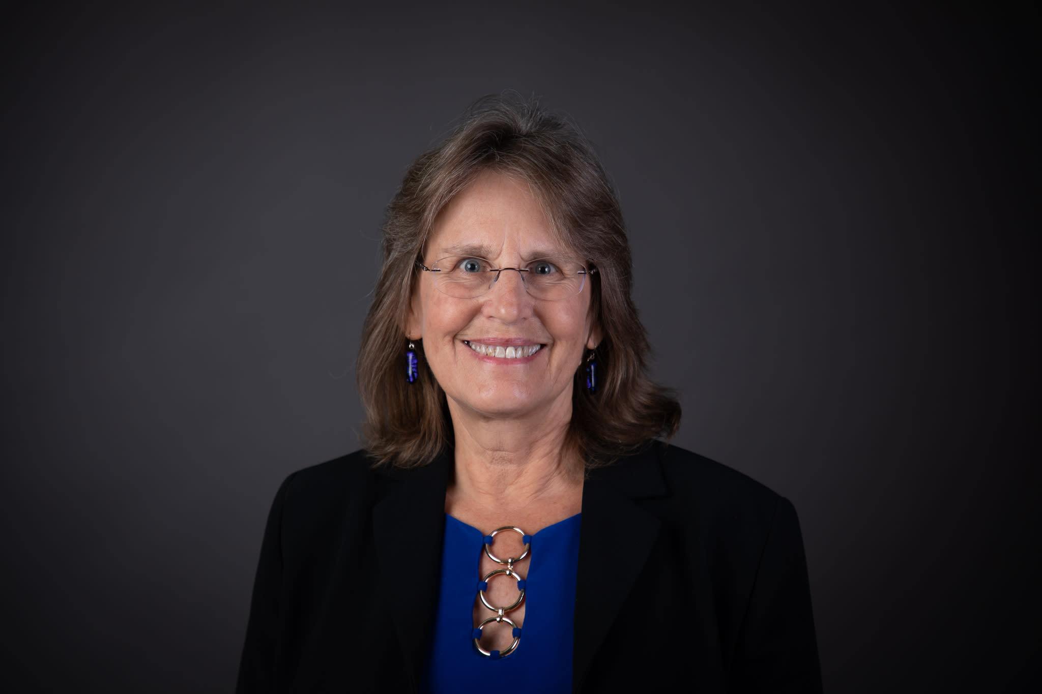 Yvonne wearing a royal blue shirt and a dark suit jacket.