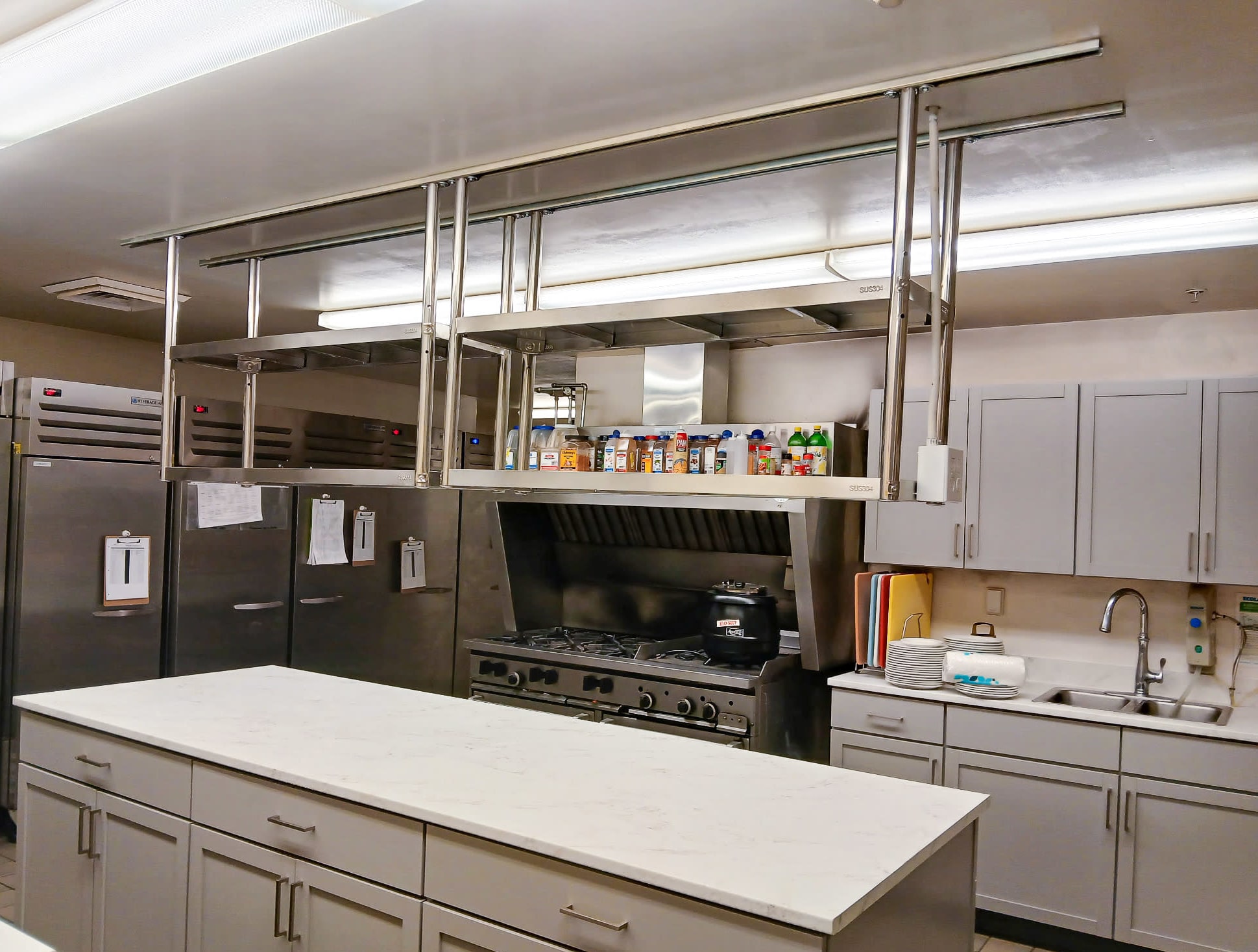 A commercial kitchen with grey cabinets, countertops, and shelving.