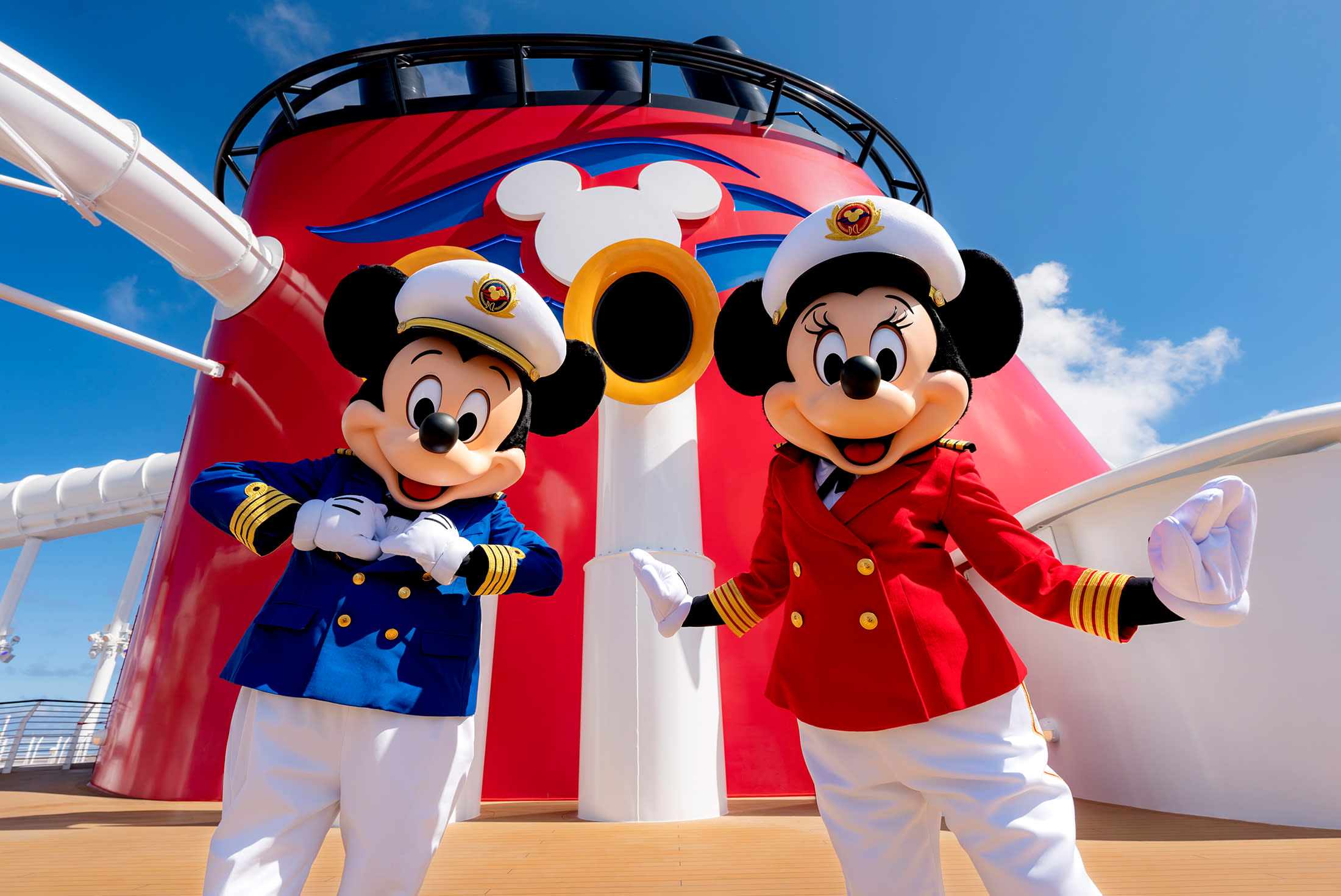 Mickey Mouse and Minnie Mouse standing in front of red cruise ship funnel