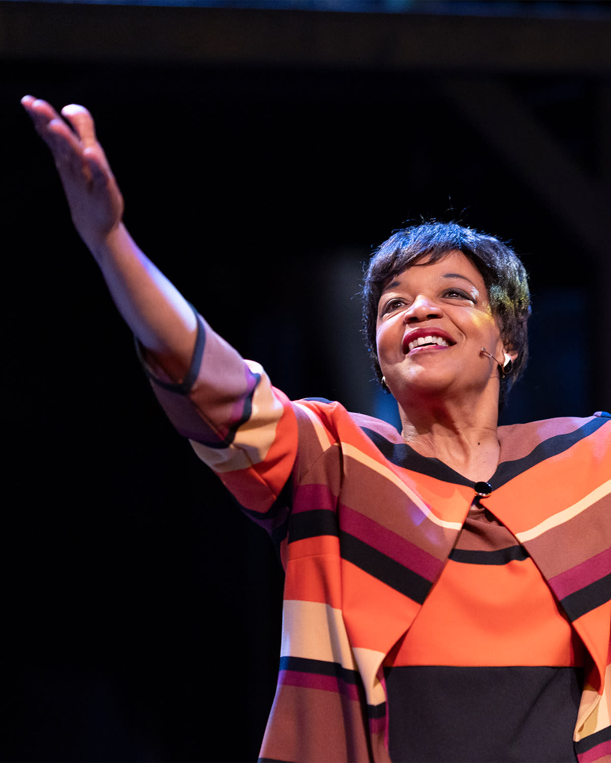 A black actress joyously smiling with arms wide