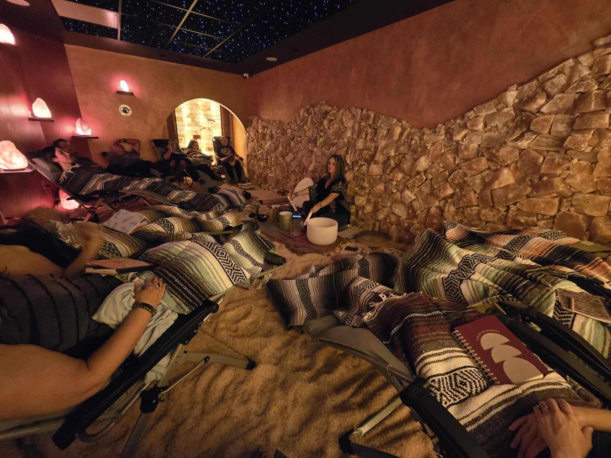 People covered in blankets while reclining in the salt cave during a sound bath