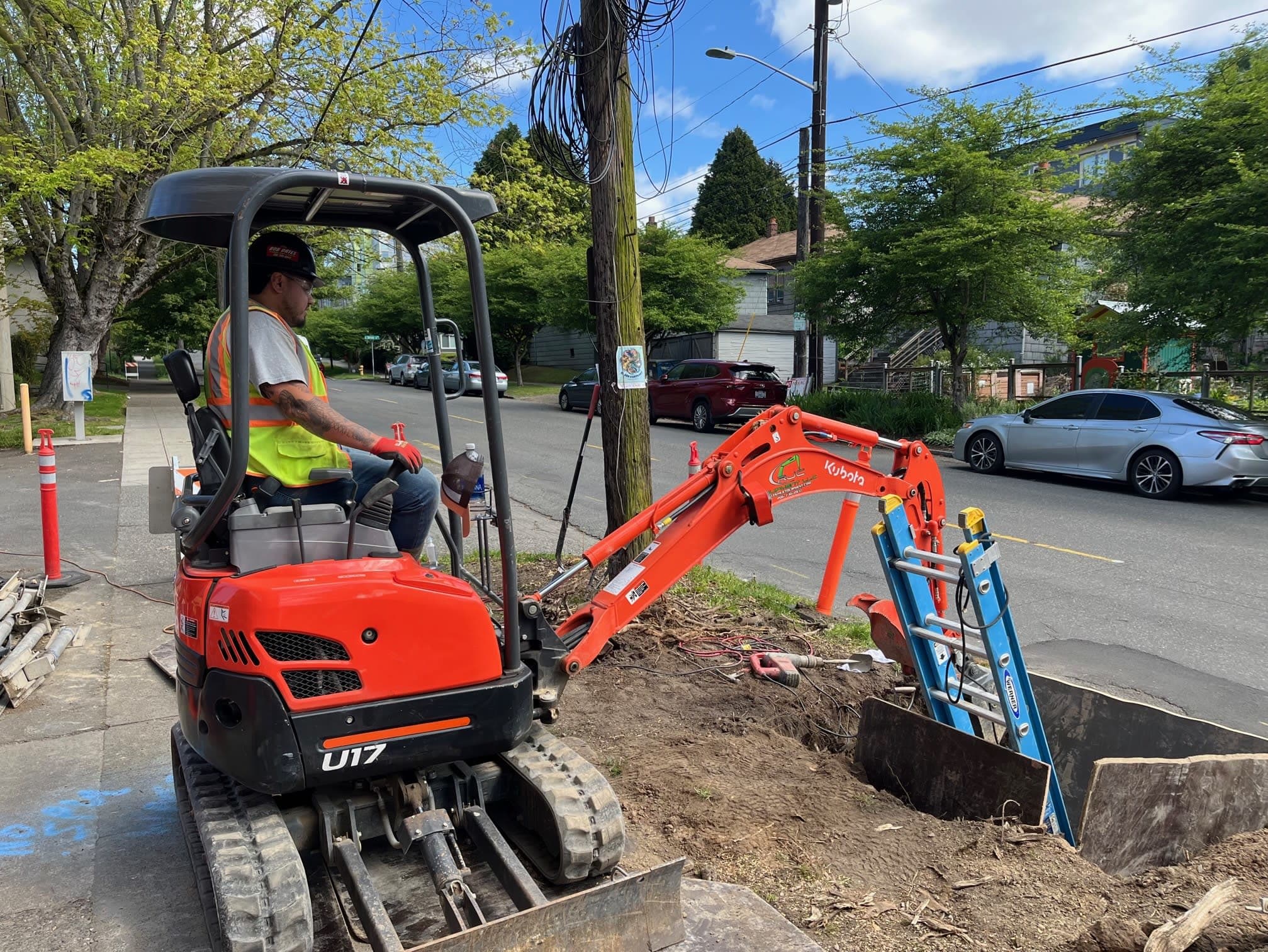 A Bob Oates techician using a small excavator near the street to access the city sewer line