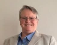 Blond woman in blue shirt and tan blazer