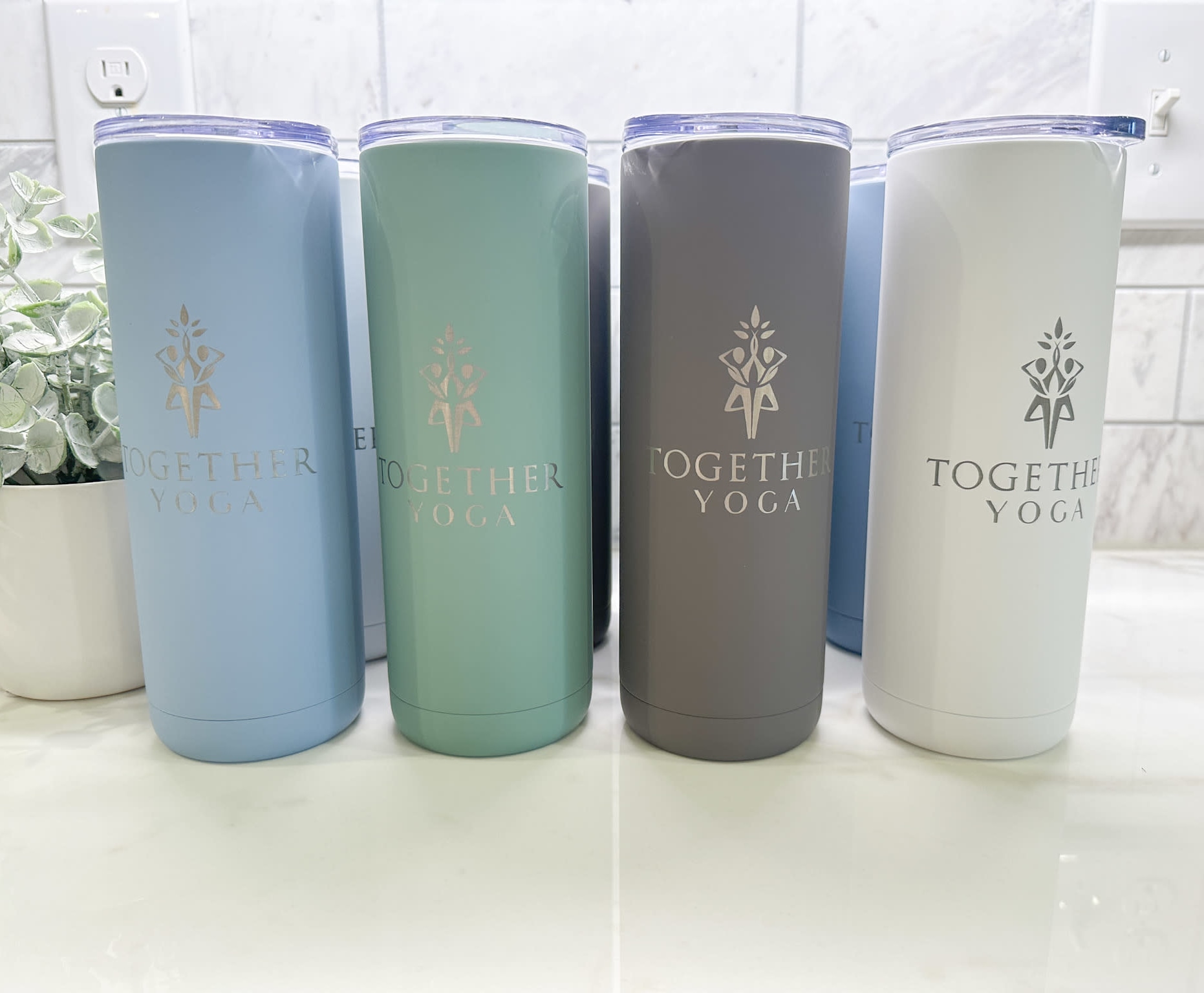 custom engraved soft colored tumblers with the together yoga logo engraved onto them to reveal the stainless steel underneath