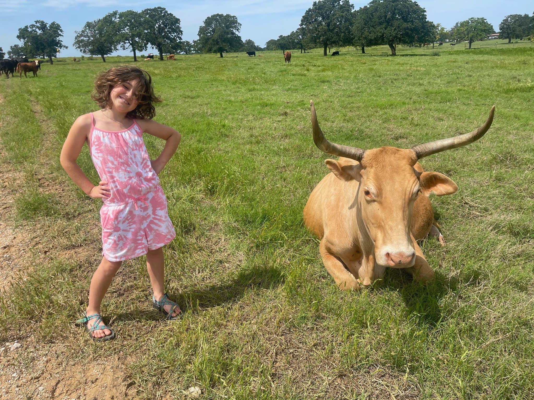 girl standing next to cow