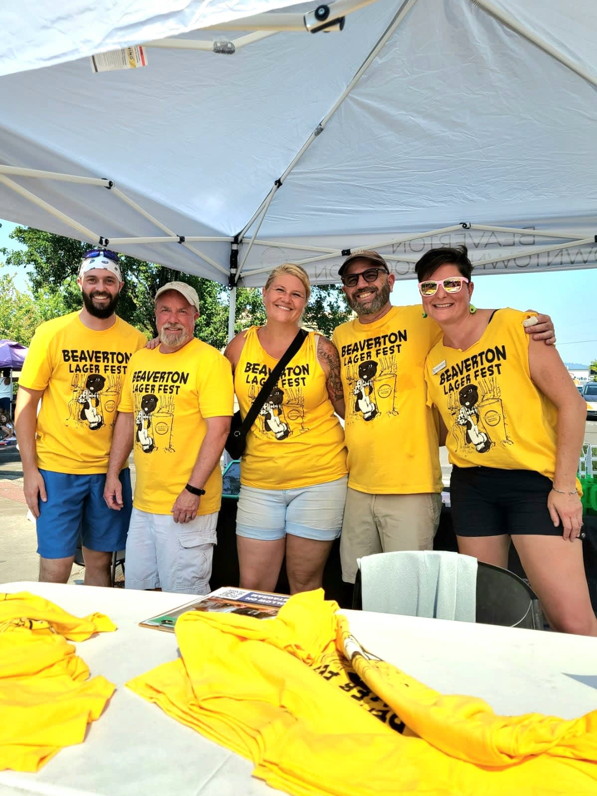 Five adults under a canopy where bright yellow Lagerfest t-shirts