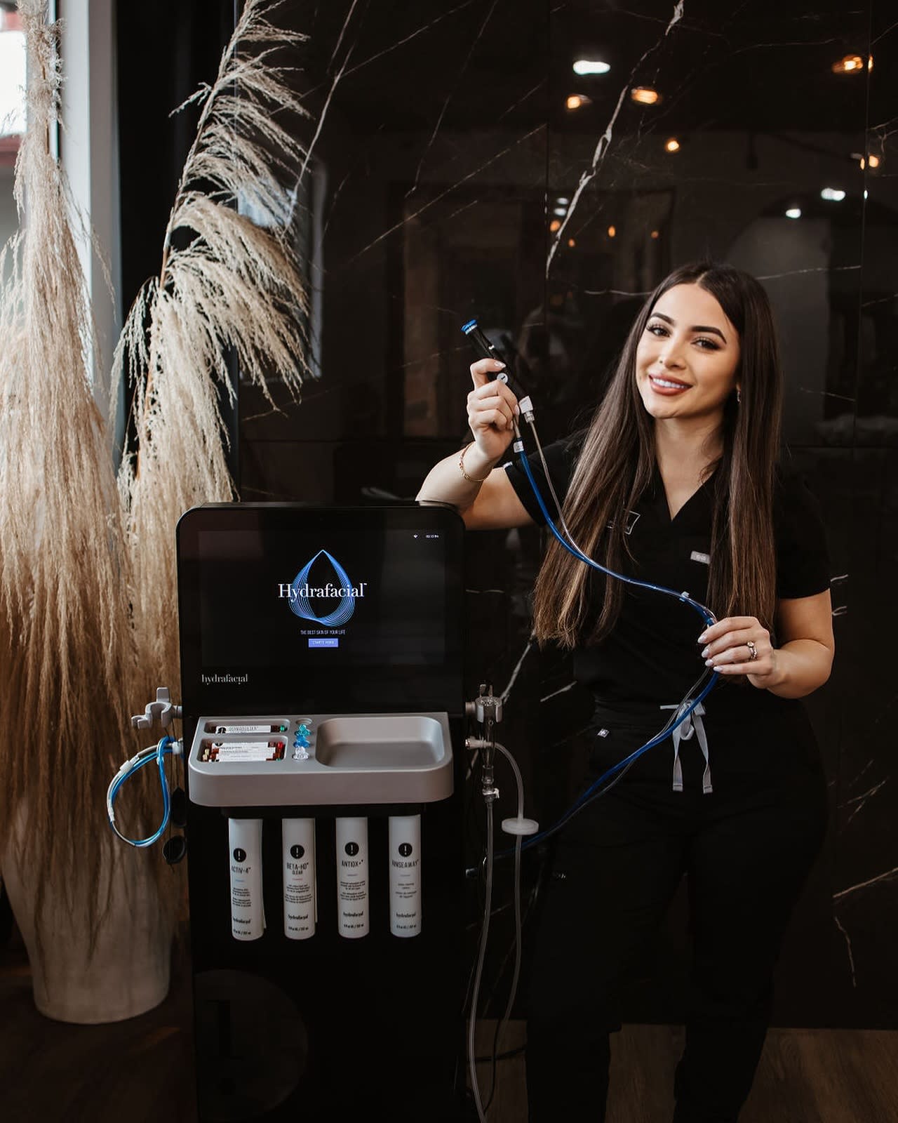 Licensed esthetician at Jaliza Sedona Luxury Med Spa in West Sedona smiling beside a Hydrafacial machine