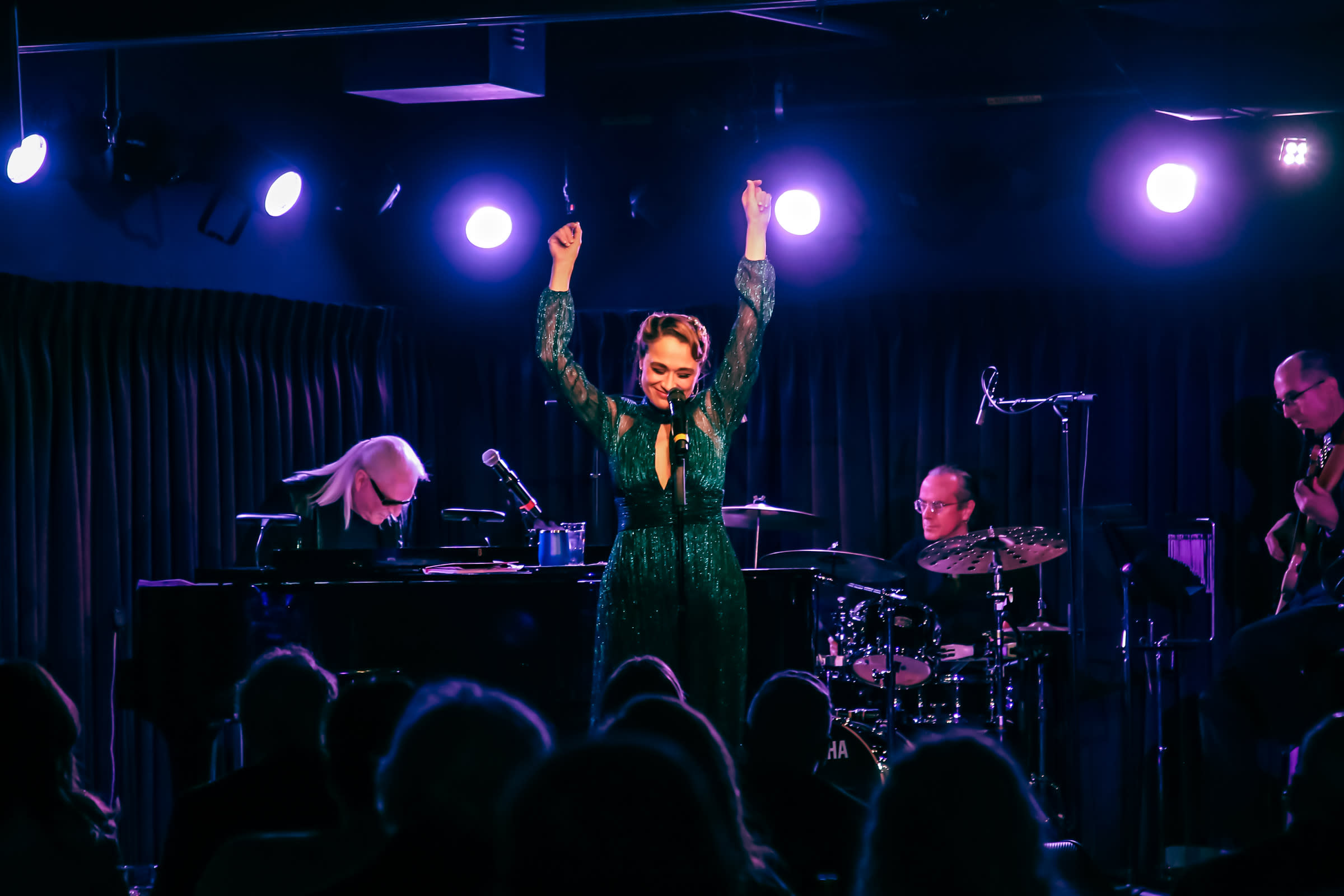 Lianne Marie Dobbs, wearing a long shimmery blue / green dress, in performance in New York City with music director