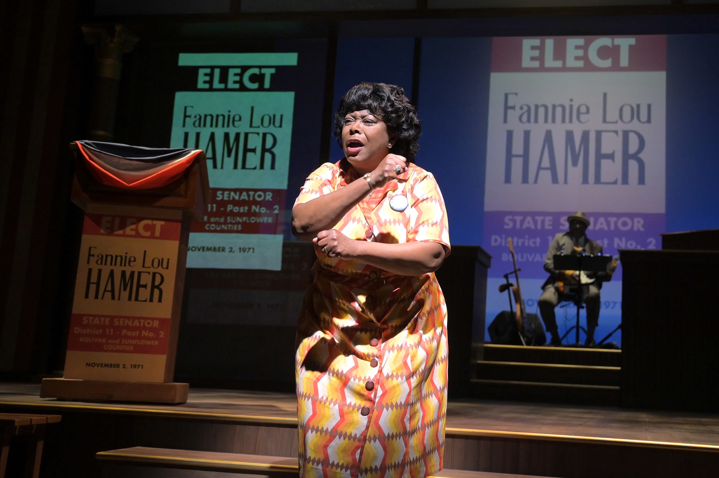 Greta Oglesby as civil rights activist Fannie Lou Hamer swings her arms in front of "Elect Fannie Lou Hamer" signs.