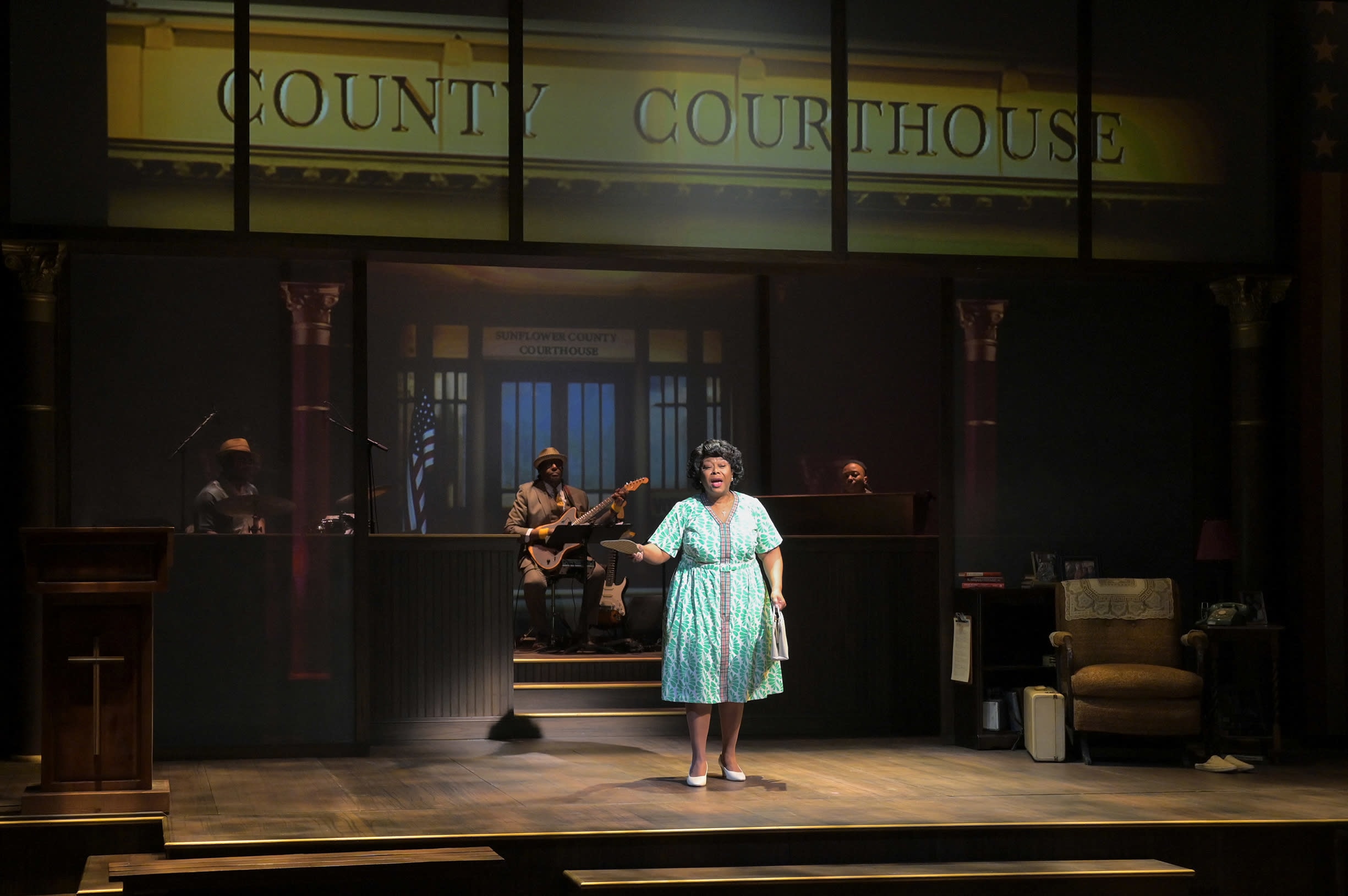 Greta Oglesby as civil rights activist Fannie Lou Hamer addresses the audience in front of a live band and courtroom set.