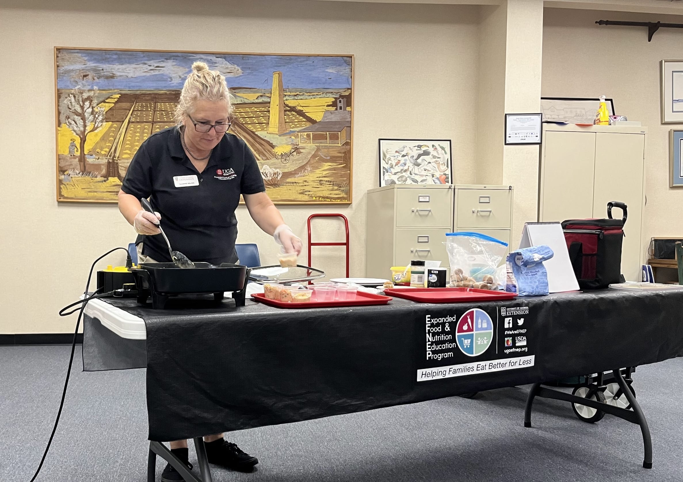 Woman preparing food in electric skillet with ingredients on display on the table next to the skillet