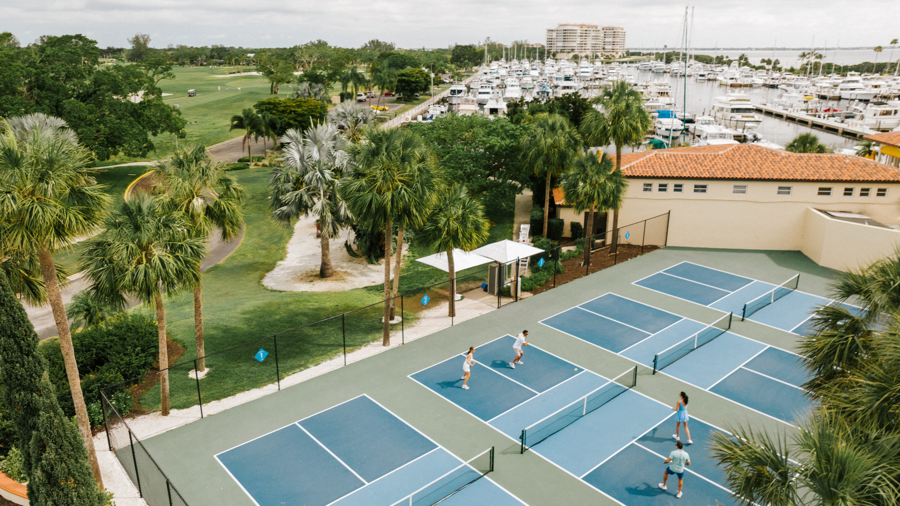 Aerial of pickleball courts, golf course, and marina slips