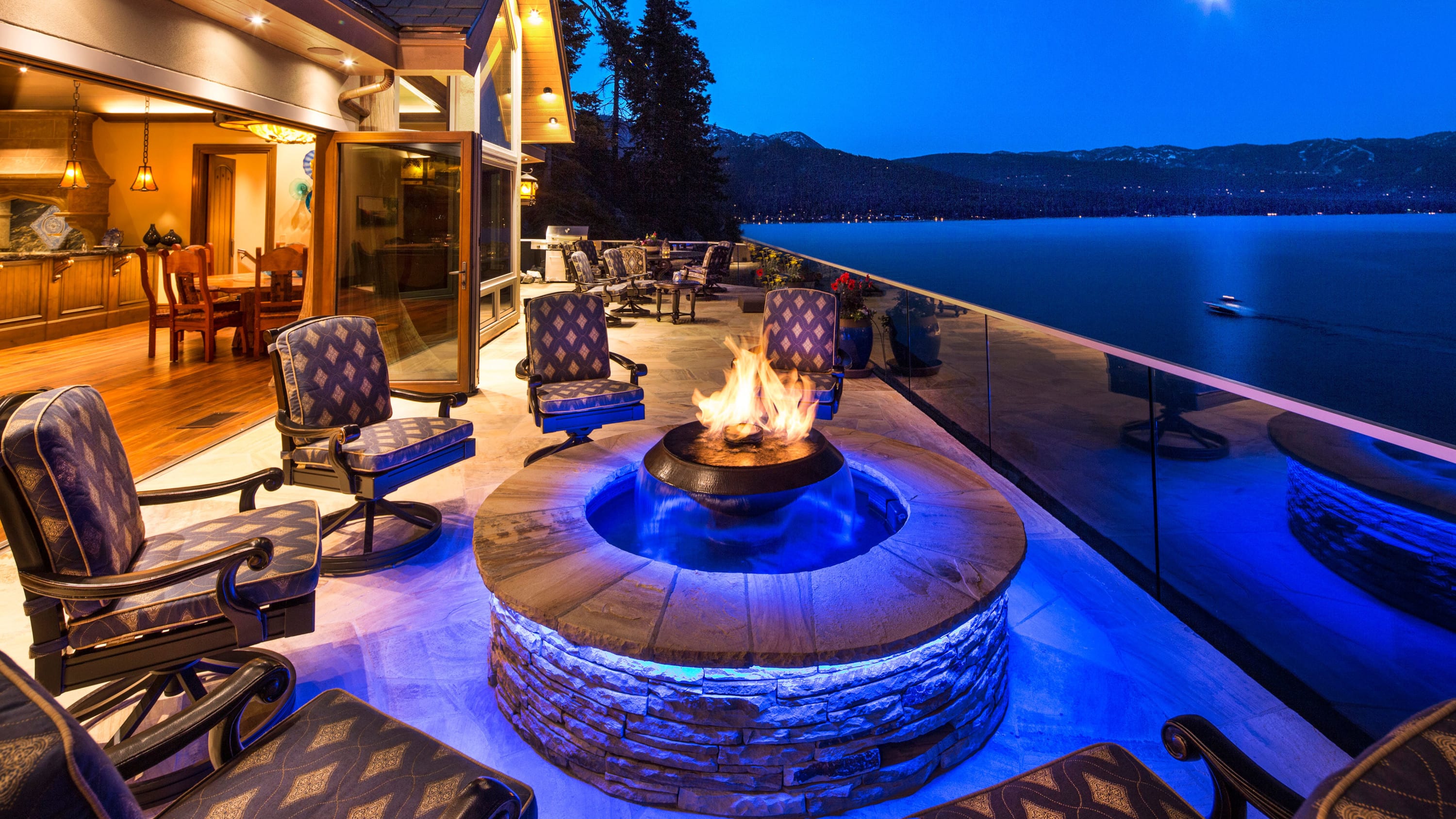 A round fire-pit lighted by blue LED on a deck overlooking Lake Tahoe