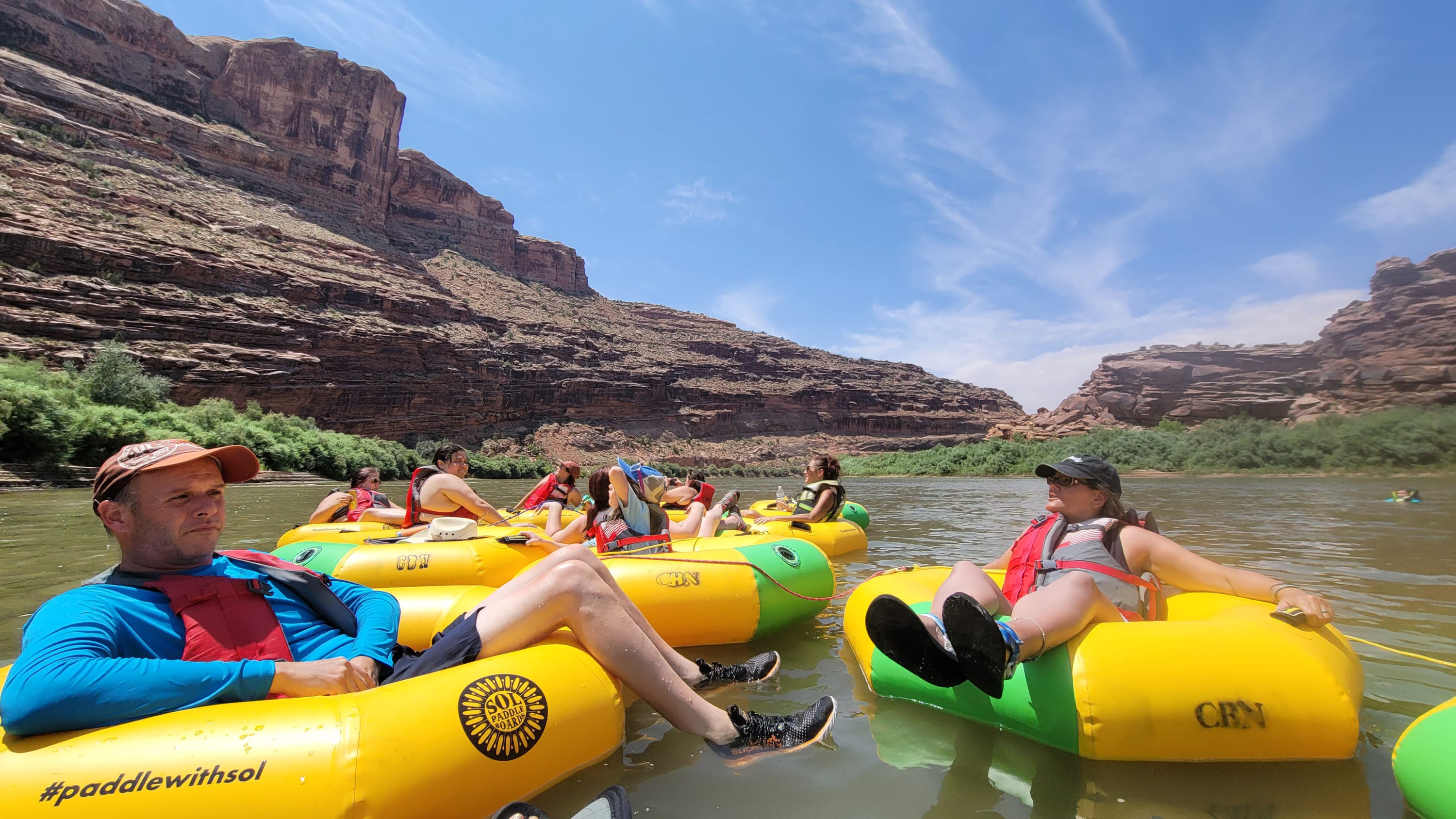 Friends linking tubes and laughing during a tubing trip near Moab