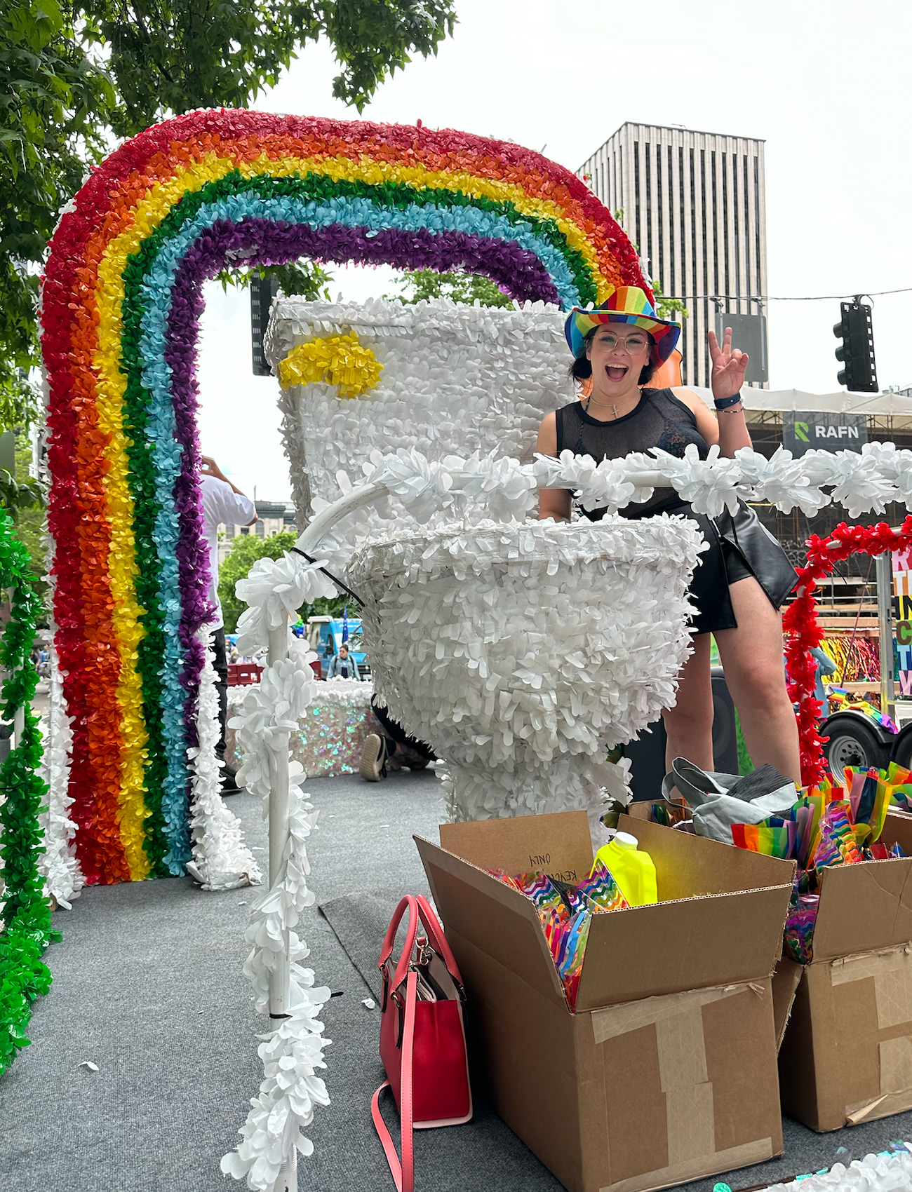 Bob Oates team member smiling with a Pride hat on, on top of the Bob Oates Pride Parade float, large rainbow float behind