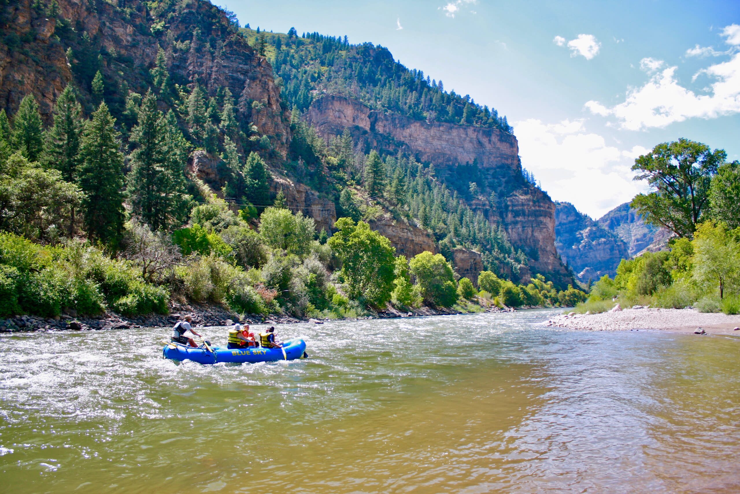 A Blue Sky Rafting boat floats down the Colorado River while soaking in the views of the stunning Glenwood Canyon.