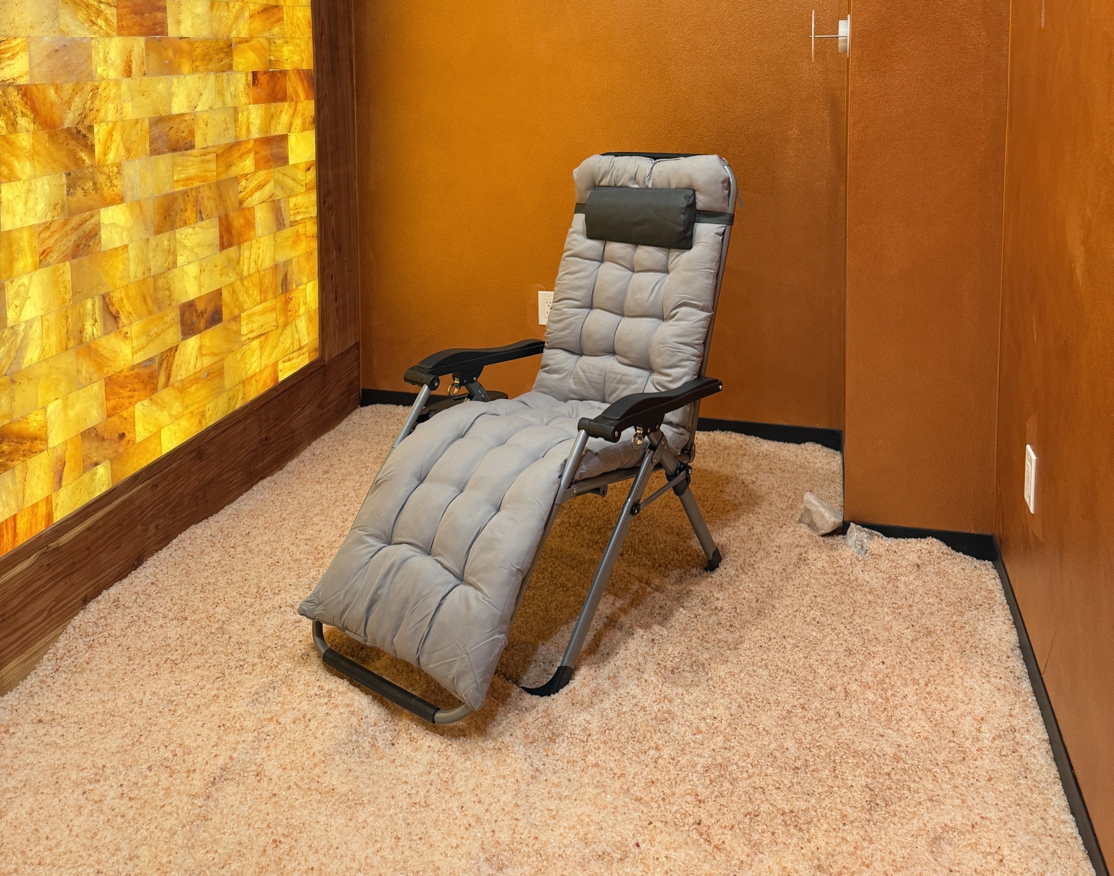 A reclining chair sits in a small salt cave next to an illuminated wall made of salt bricks
