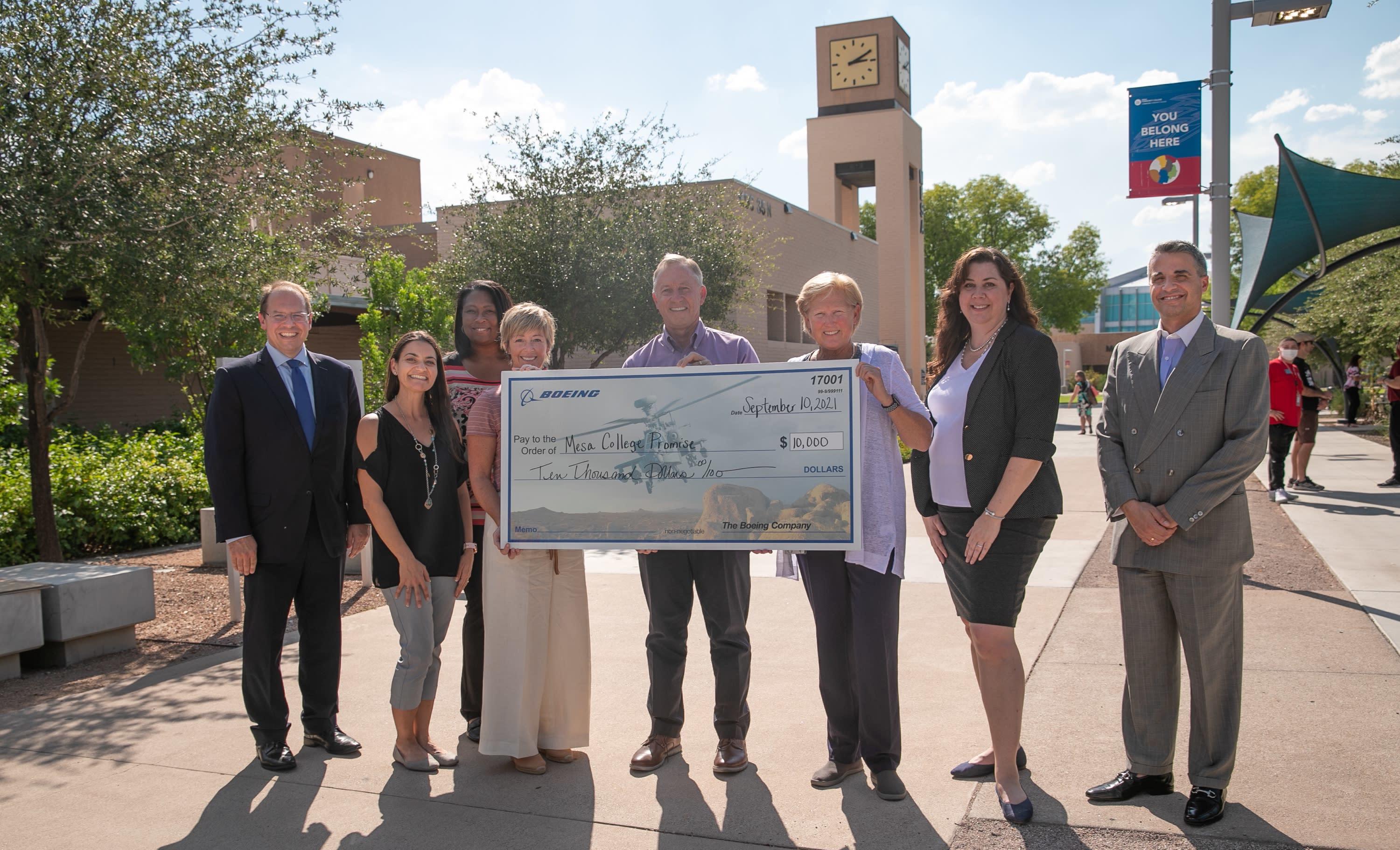 4 representatives from The Boeing Company, Mesa Mayor John Giles, and 3 MCC leaders stand with oversized check for $10,000.