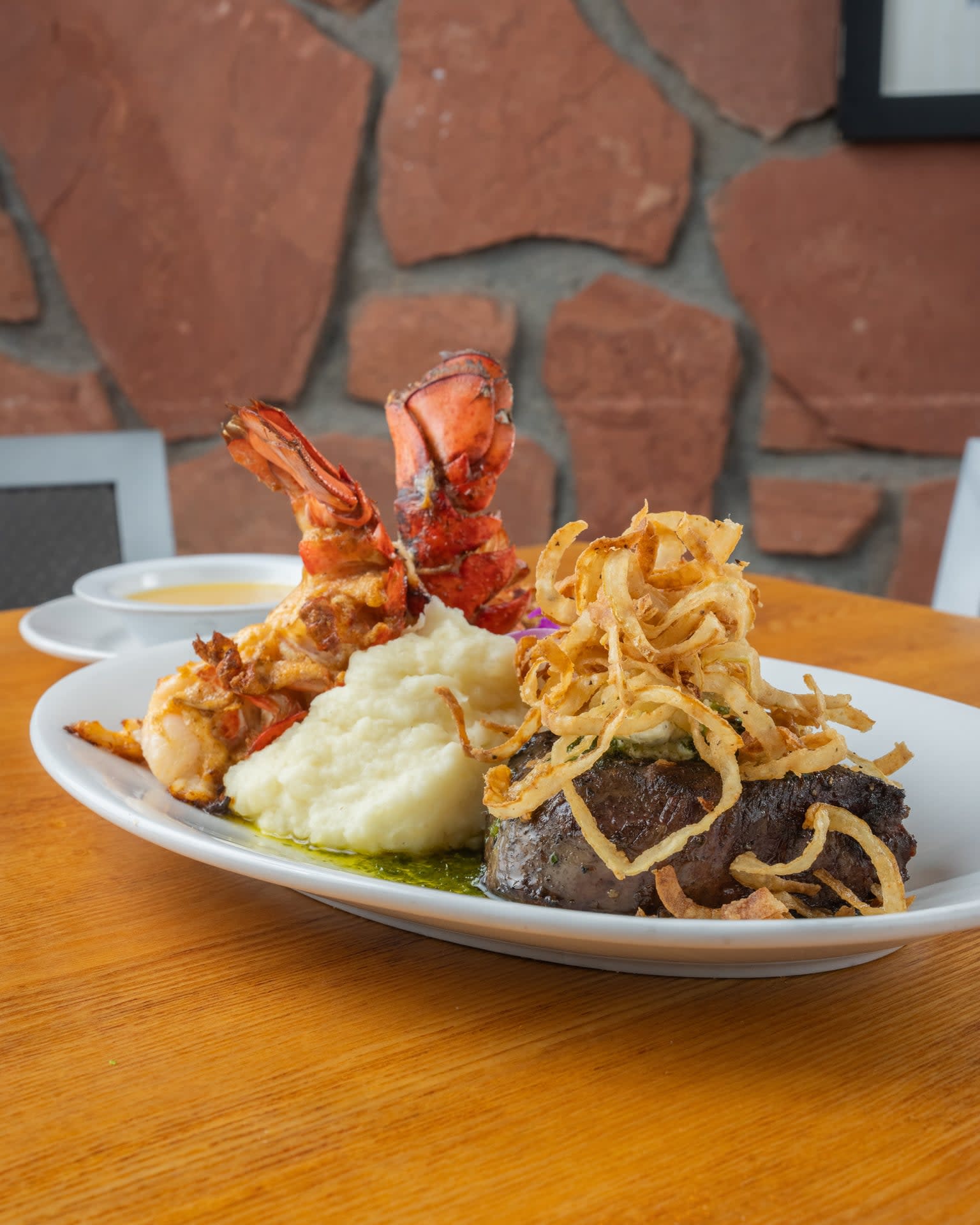 Grilled steak with lobster tail, mashed potatoes, crispy onions, and herb sauce at Mesa Grill Sedona Airport.