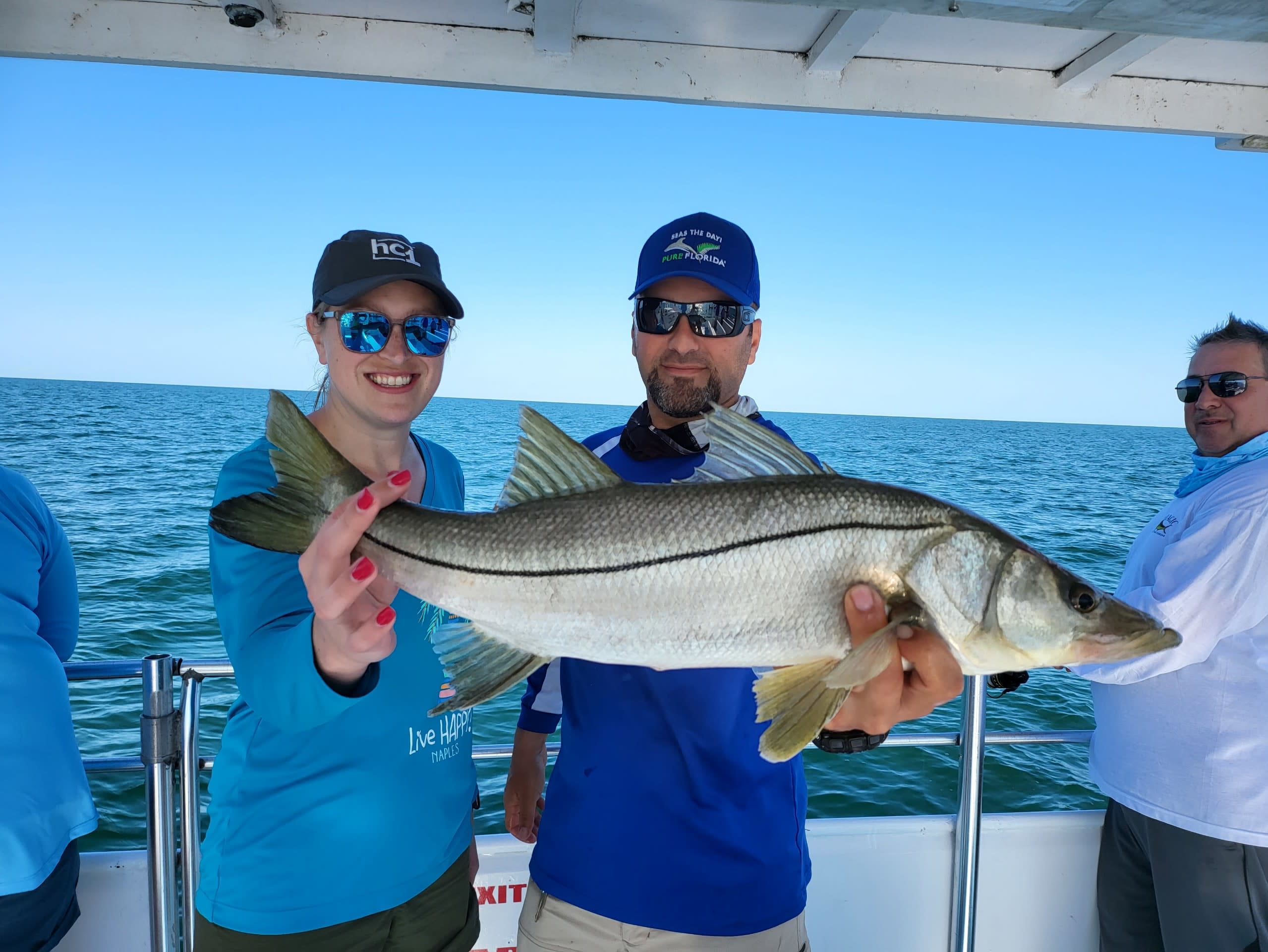 Female Guest Smiling next to Captain Holding a big fish