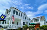 White Porch Inn Art Hotel featuring a classic white exterior, wraparound porch with rocking chairs, and a lush garden welcomi