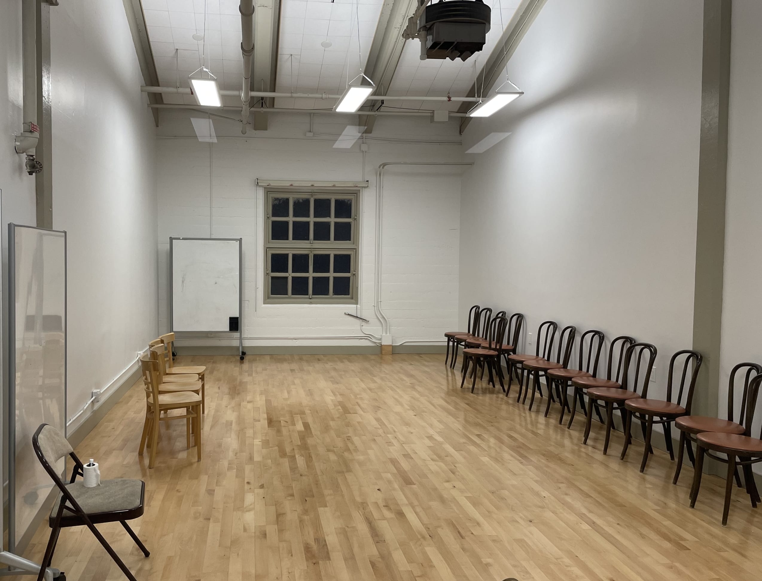 Room with wooden floor, white walls, and chairs