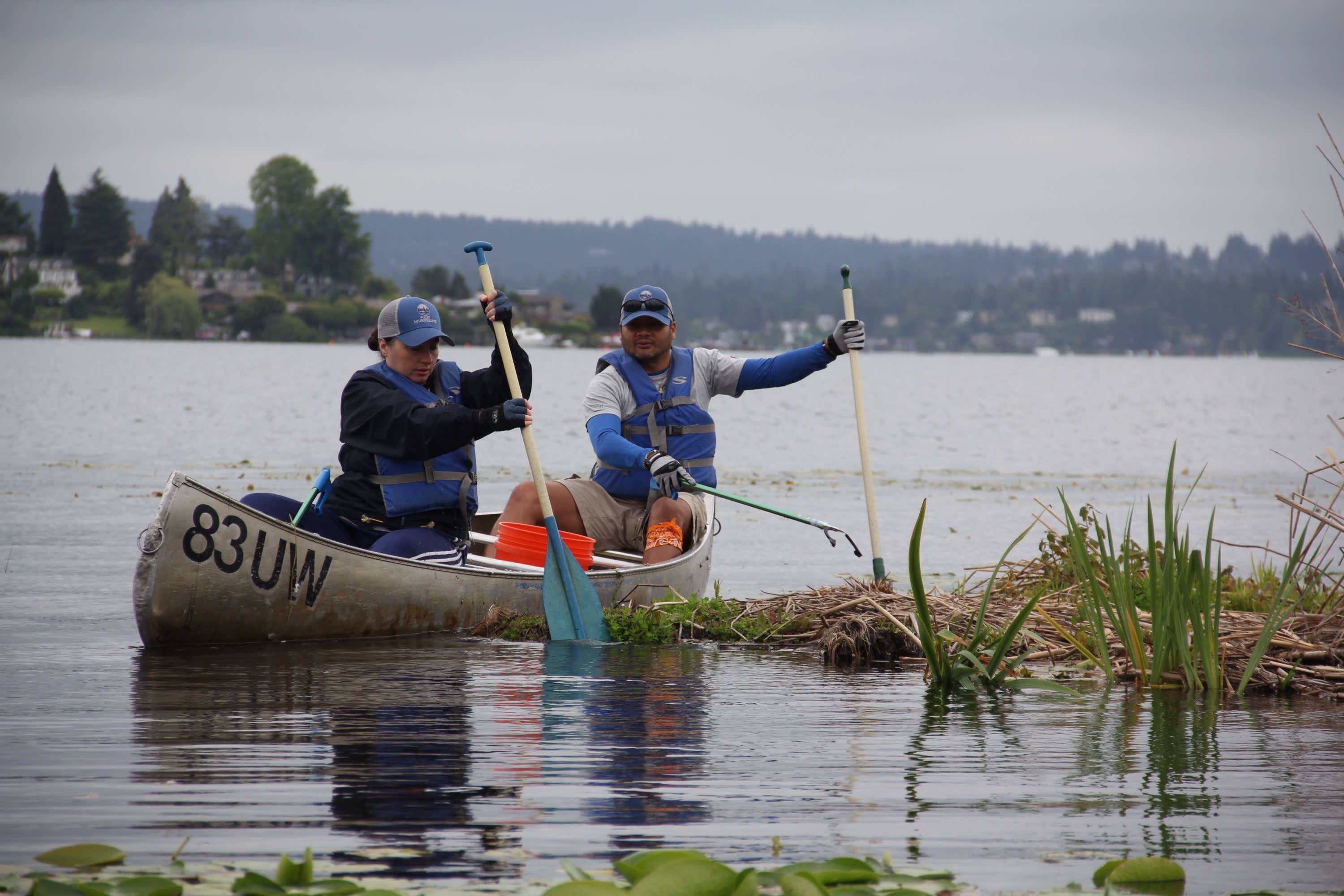 Two kayakers grabbing marine debris and plastic out of the water