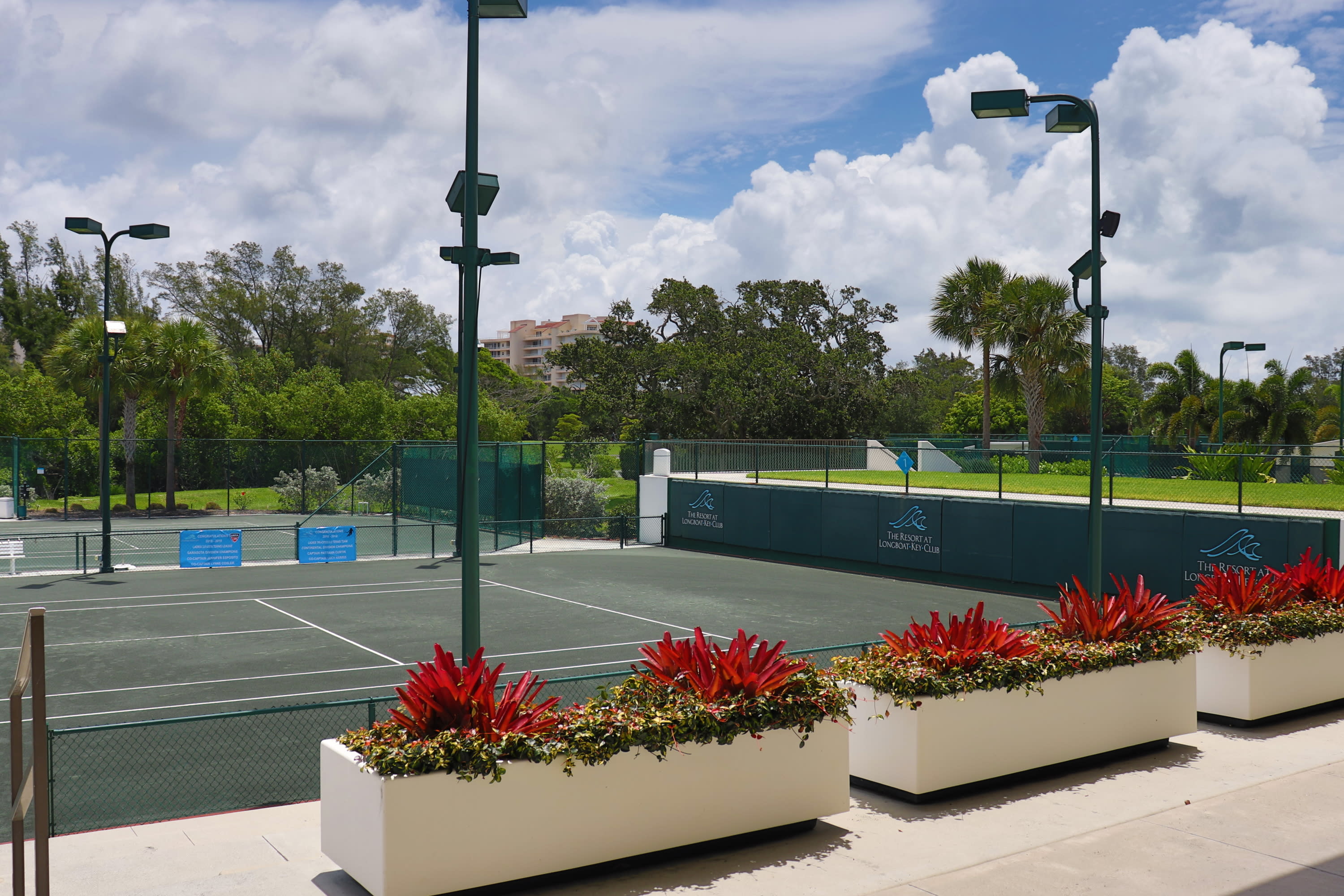 white planter boxes of colorful plants overlooking a tennis court
