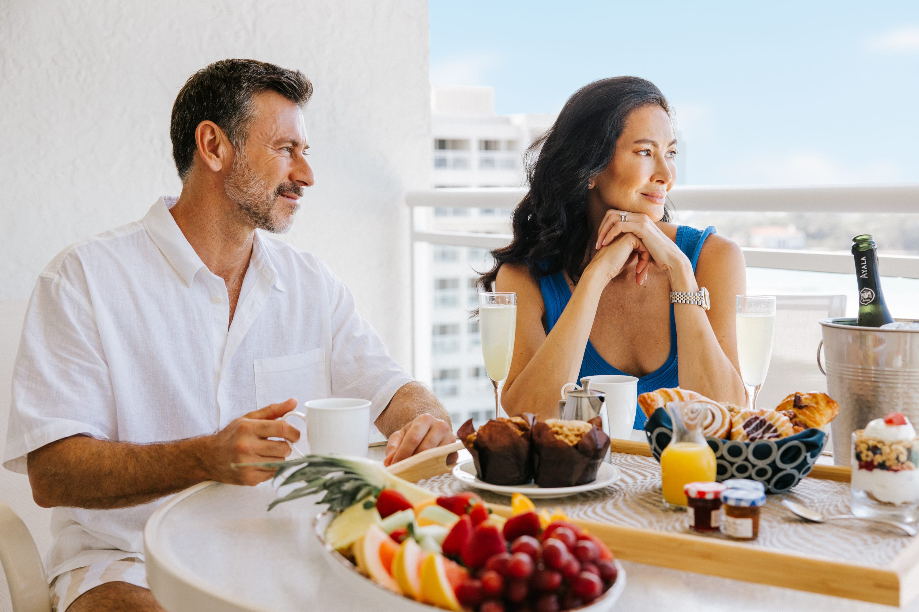 Couple on balcony of hotel enjoying breakfast overlooking the beach