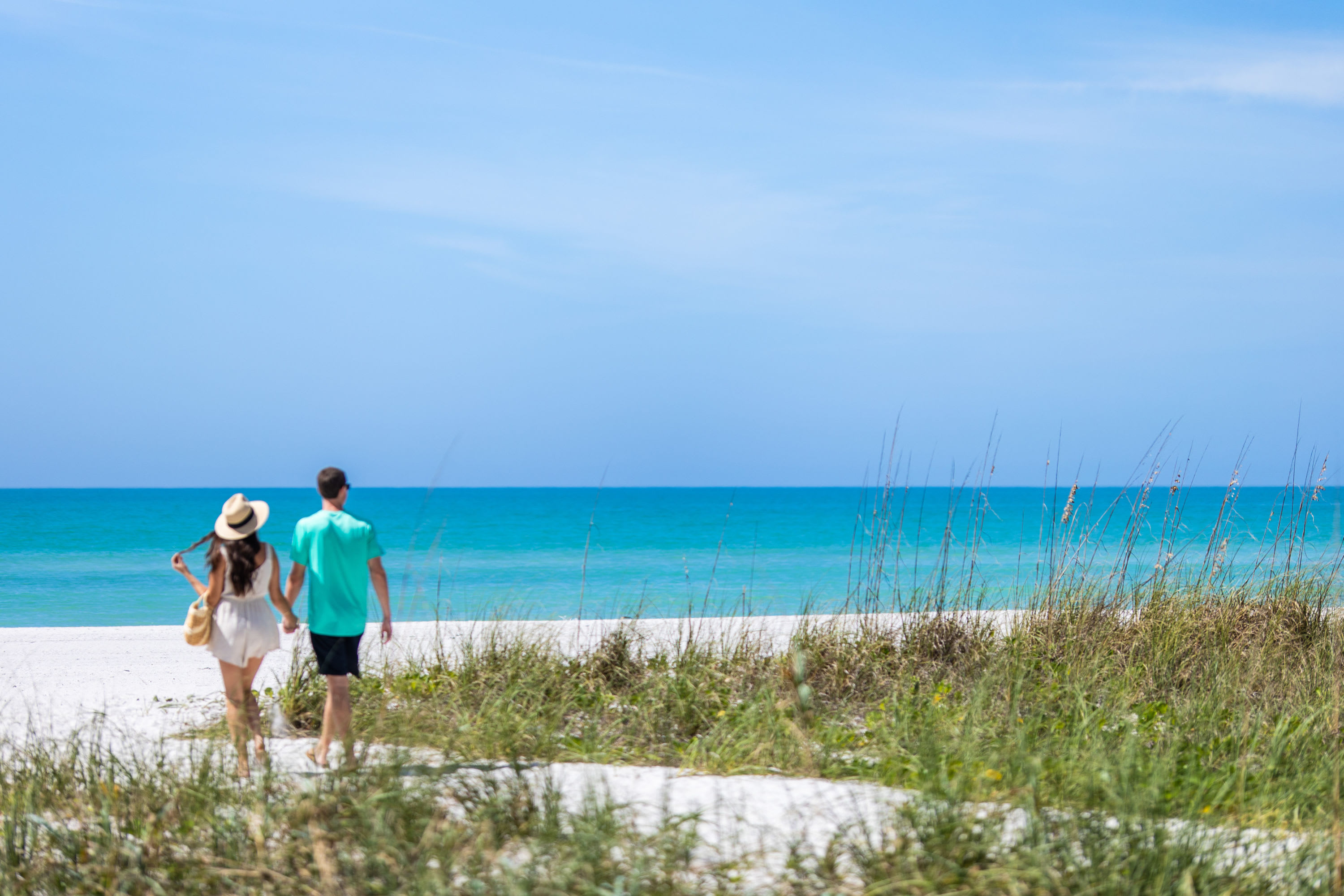 Couple walking on a sand path on the beach near sea oats