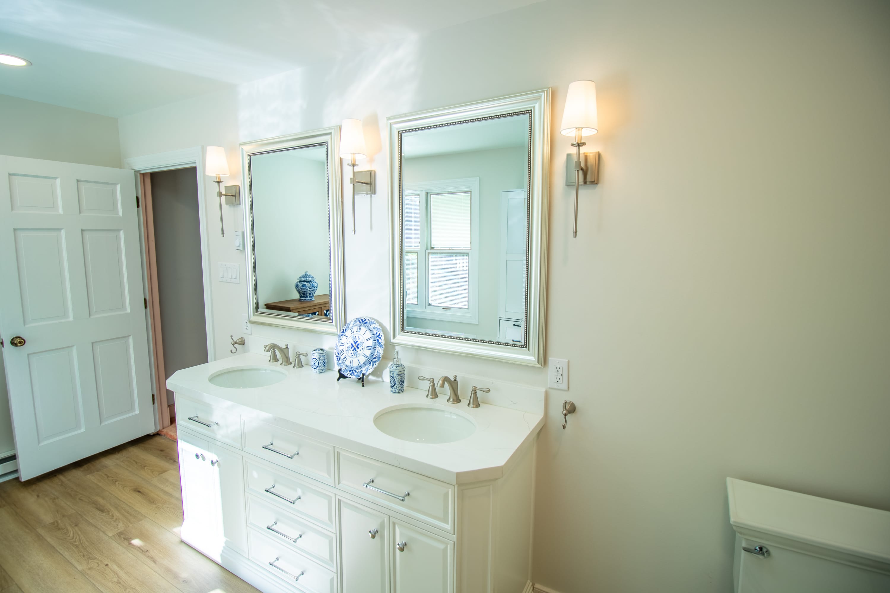 White double vanity with quartz countertop, framed mirrors, and brushed nickel sconces.