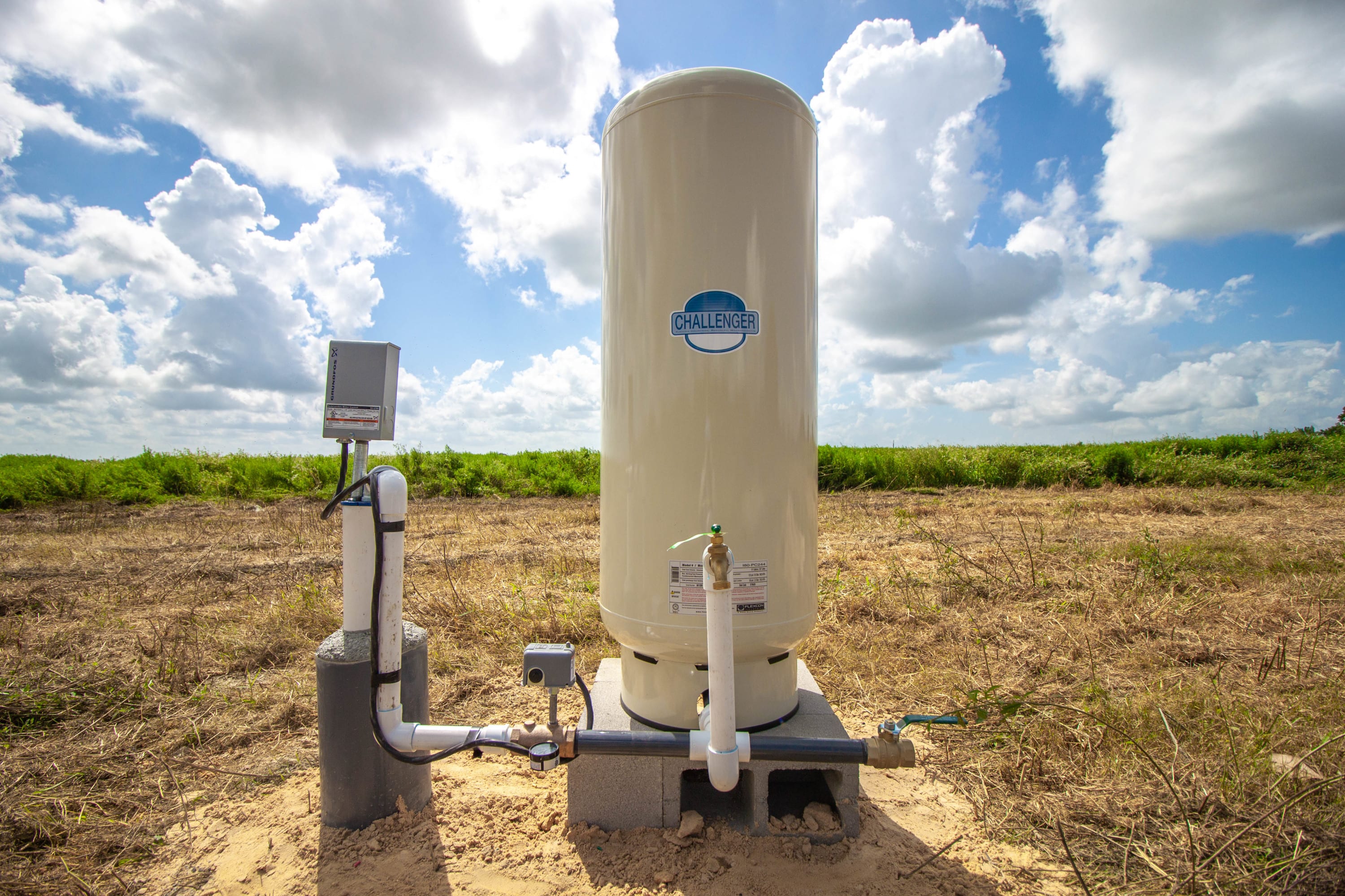 Completed water well installation with Challenger pressure tank in rural Texas field