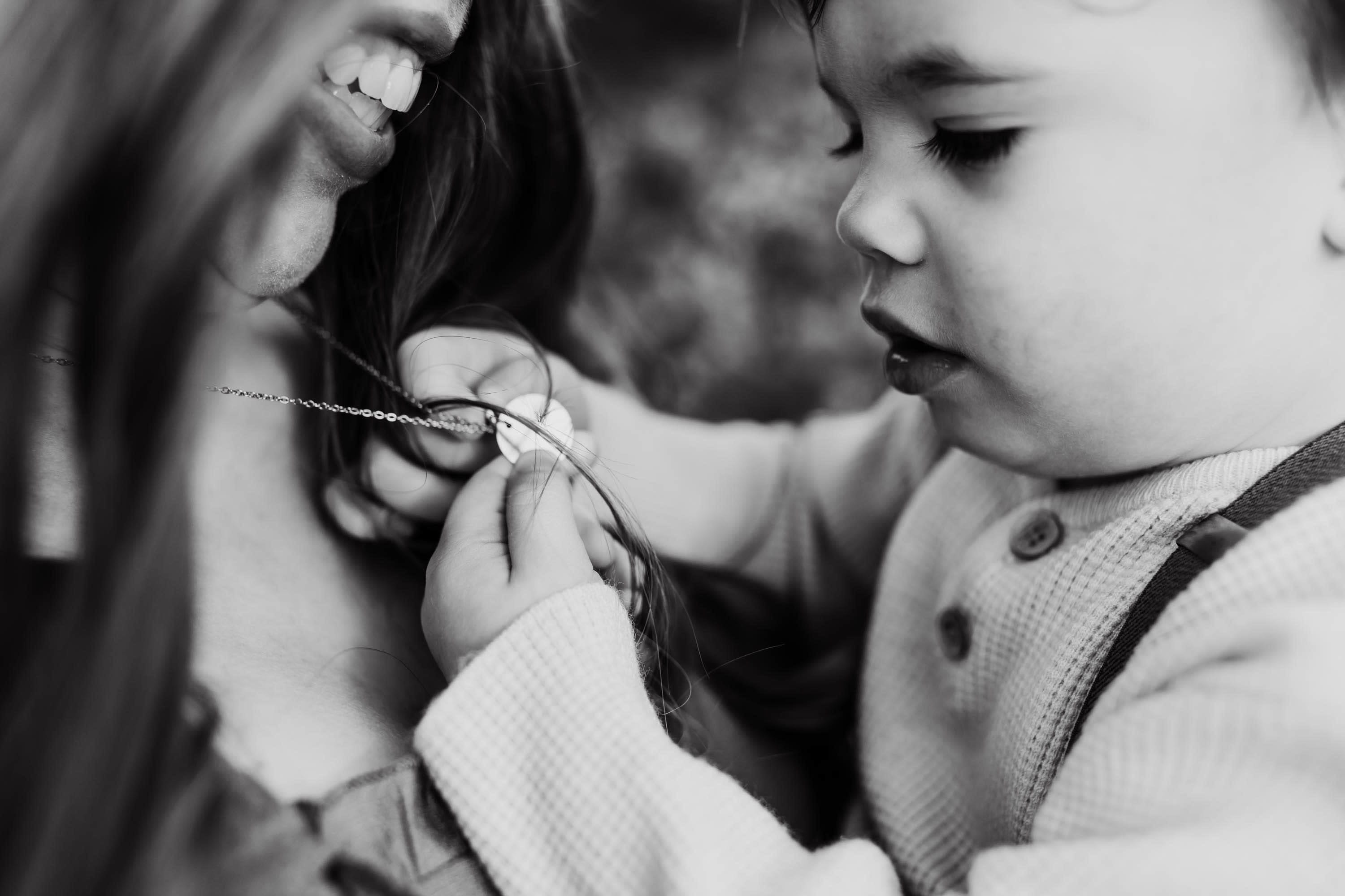 baby boy hands playing with mom's necklace
