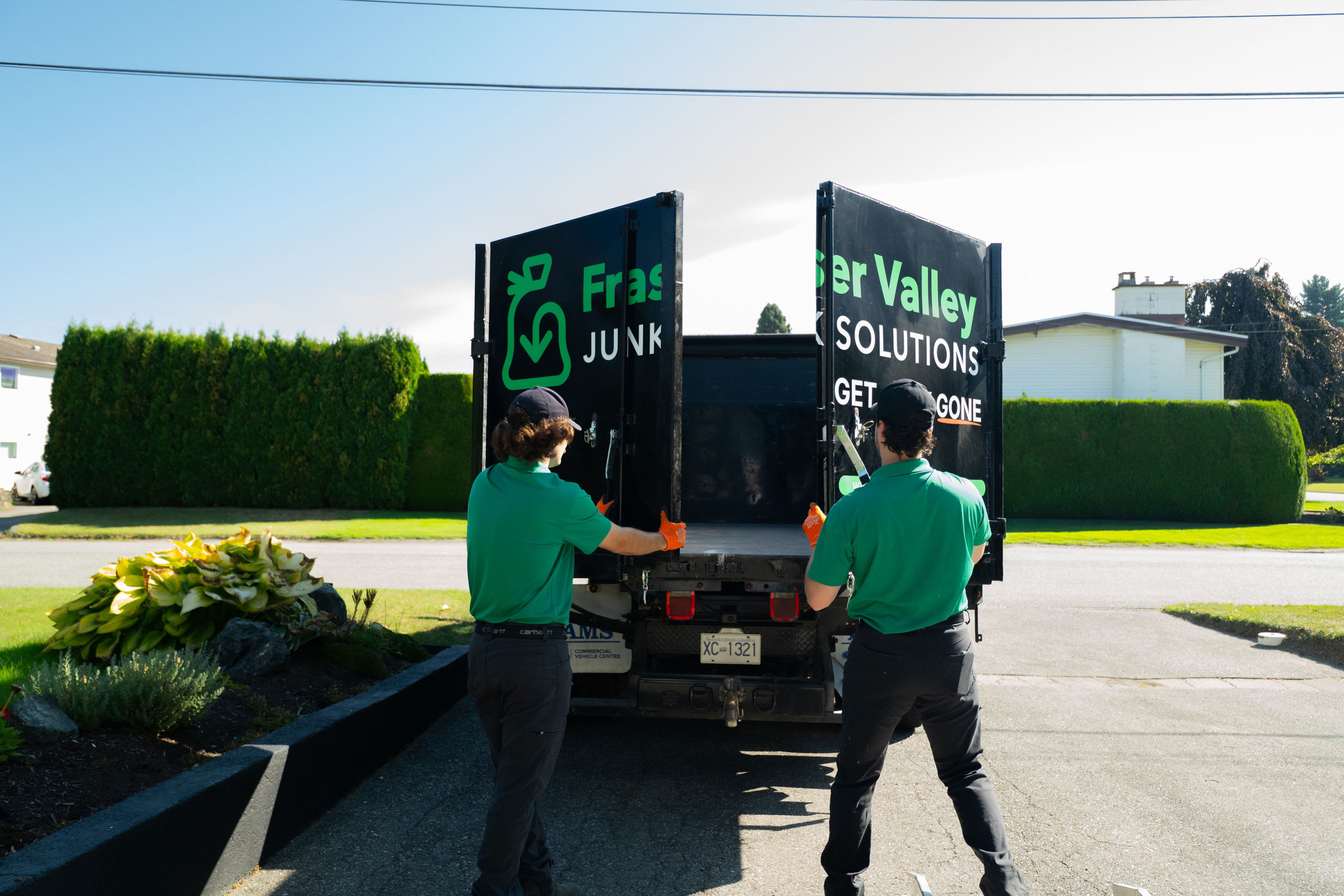 Two Fraser Valley Junk Solutions employees opening up the back doors on a FVJS truck.