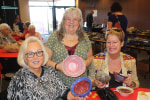 Three women showing the bowls they selected at the empty bowls event