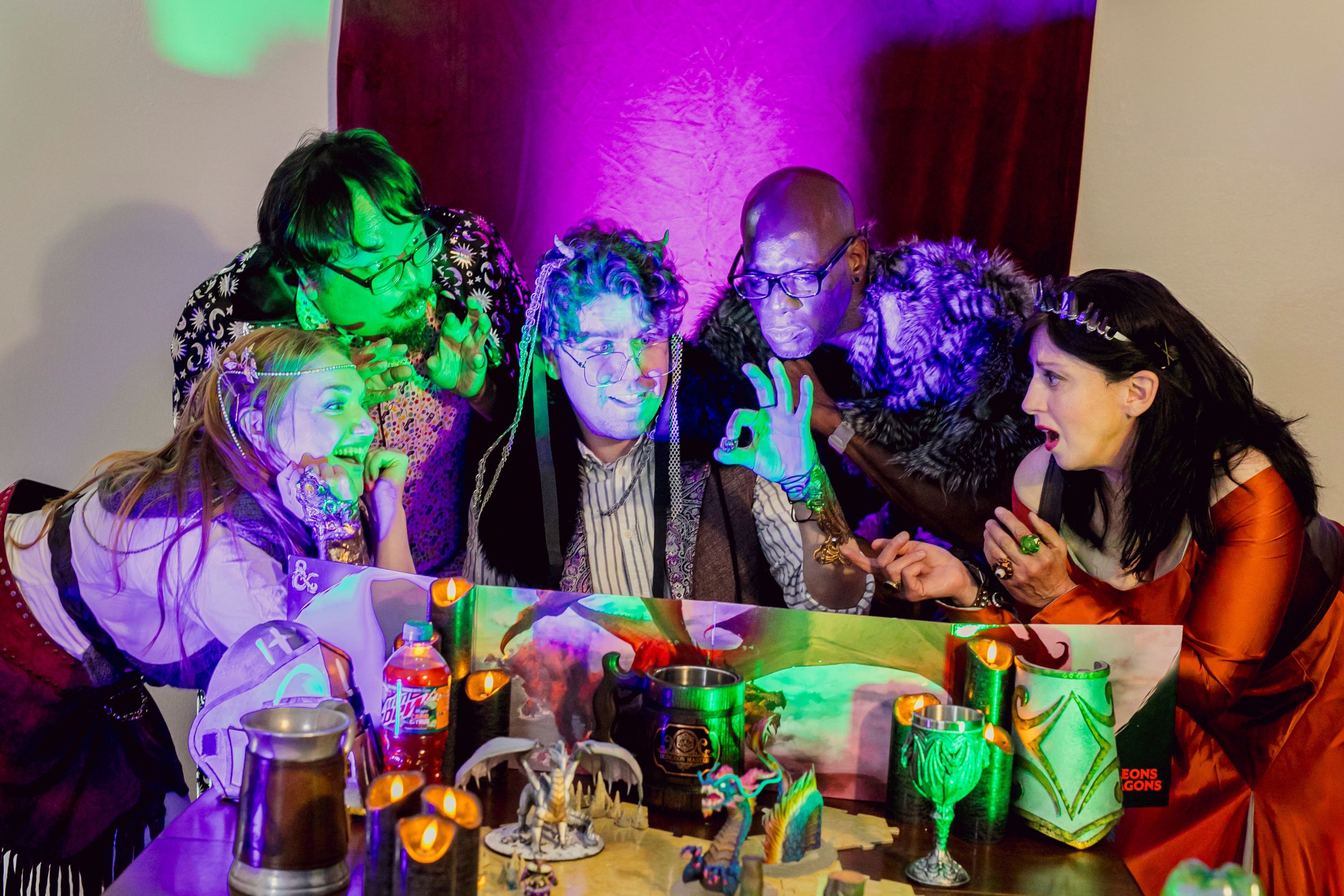 Performers Brigitte Losey, Chuck Lacson, Max Seijas, Derek Jones, and Melissa Claire, gathered behind a DM screen, regarding