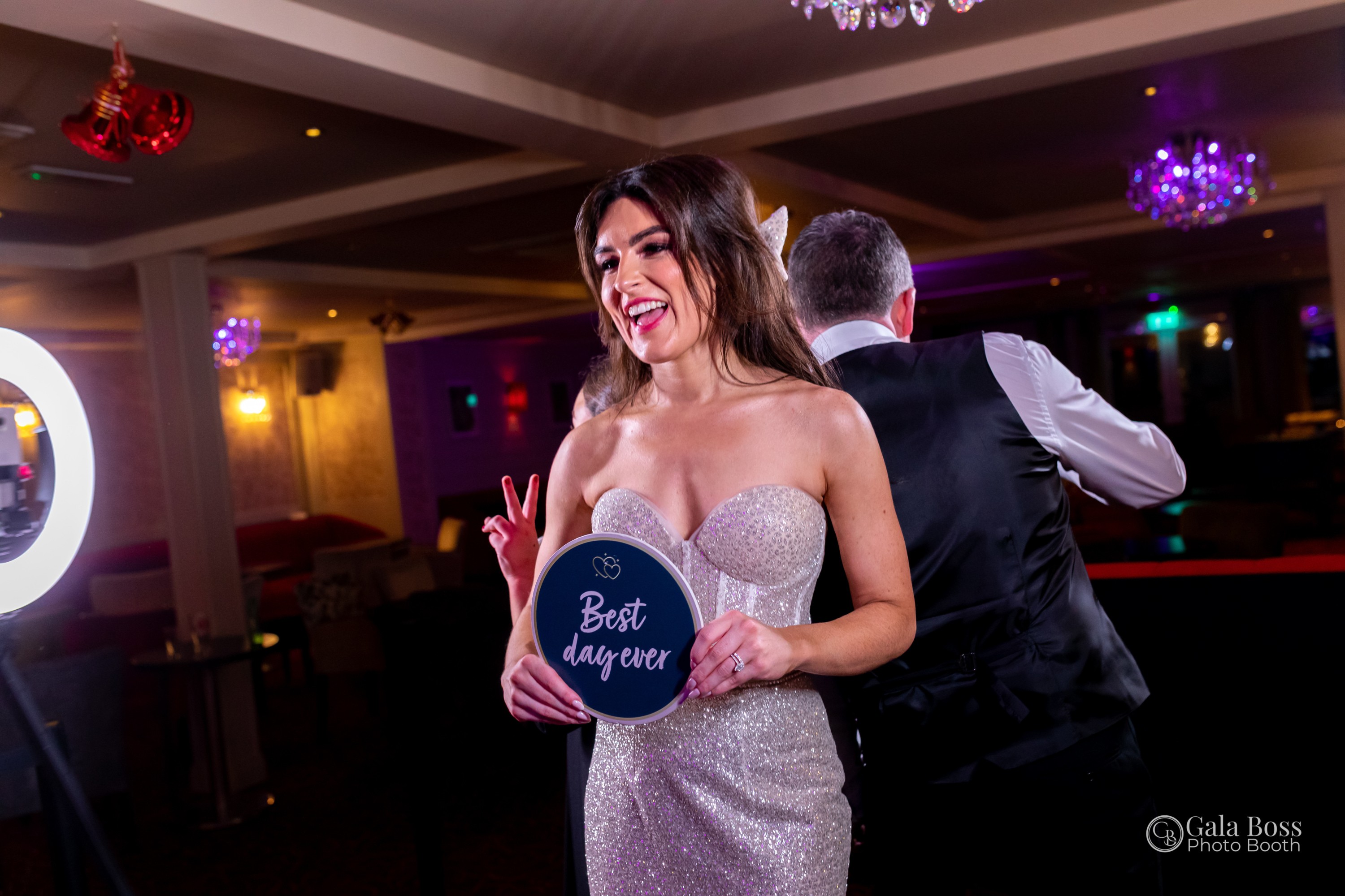 Guest smiling and posing with a “Best Day Ever” sign at a Gala Boss photo booth during a corporate celebration
